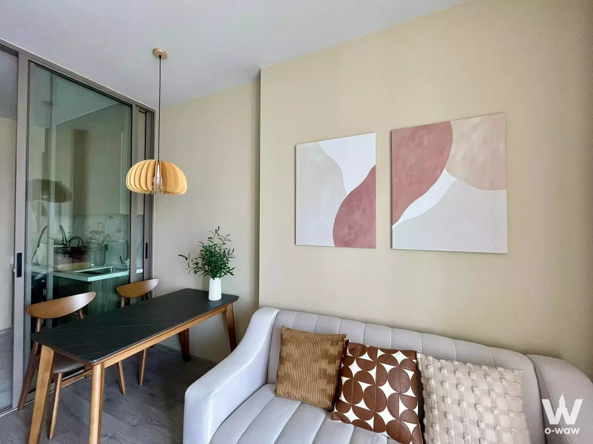 Living room with a grey sofa and wooden dining table in this 1-bed rental at Rhythm Ekkamai Estate