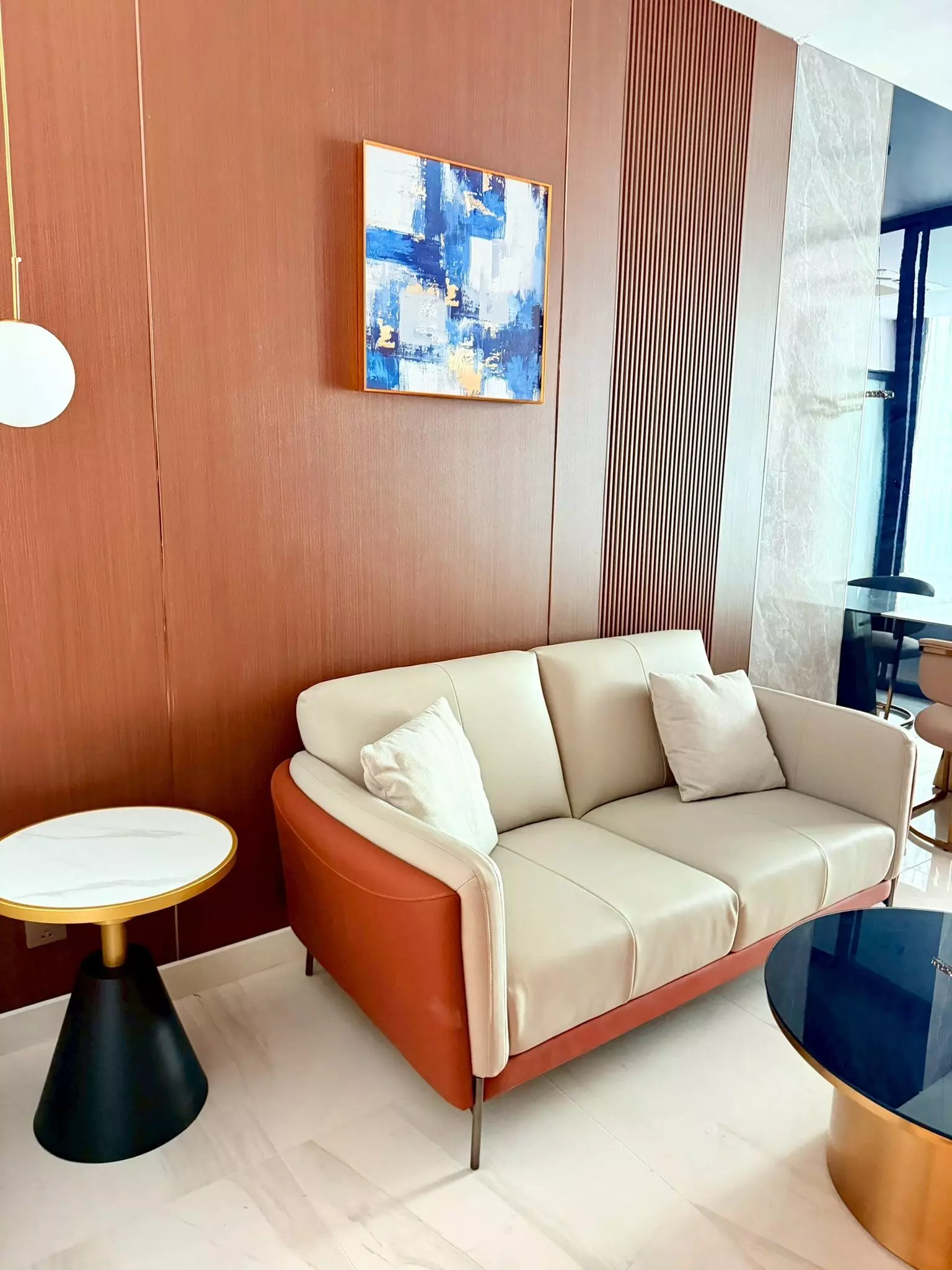 Living room in Supalai Icon Sathorn condo with burnt-orange leather sofa and wood-paneled feature wall