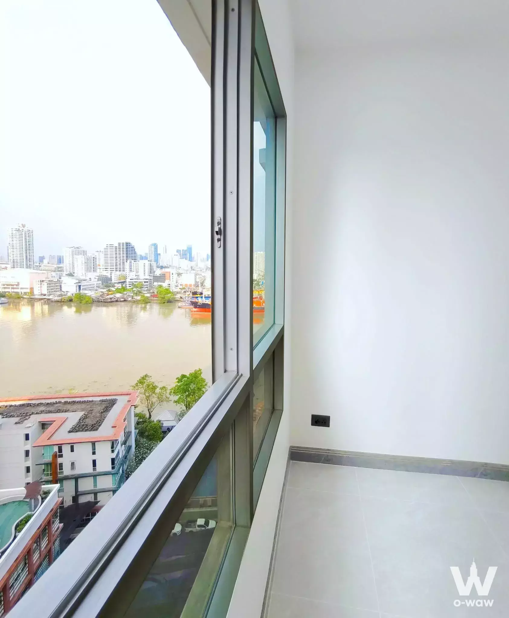Unfurnished 1-bed condo room in Ivy River with large sliding windows overlooking a wide river and city skyline