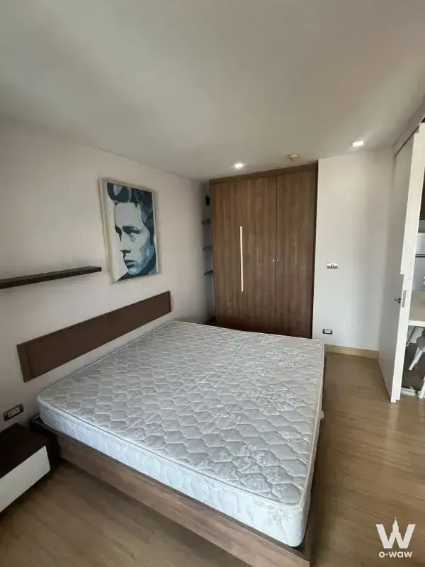 Unfurnished bedroom in a 1-bed Tree Condo Sukhumvit 42 rental with dark wood platform bed and built-in wardrobe