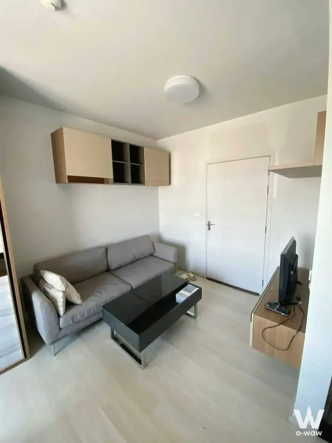 Bright living room in a 1-bed condo at Unio Ramkhamhaeng-Serithai with a grey sofa and light wood flooring