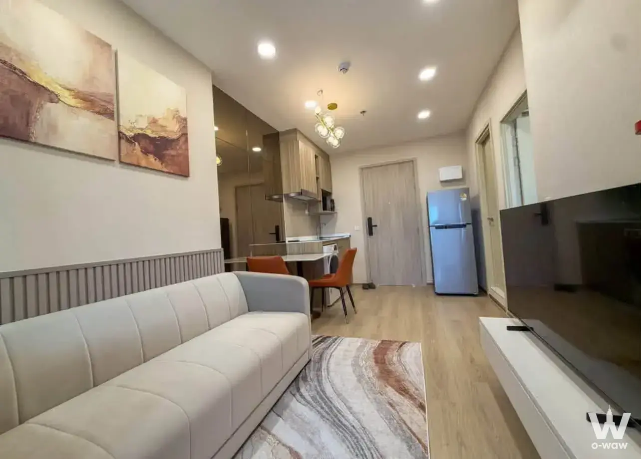 Beige leather sofa and dining area in the open-plan living space of this 2-bed condo for rent at Life Rama 4 Asoke