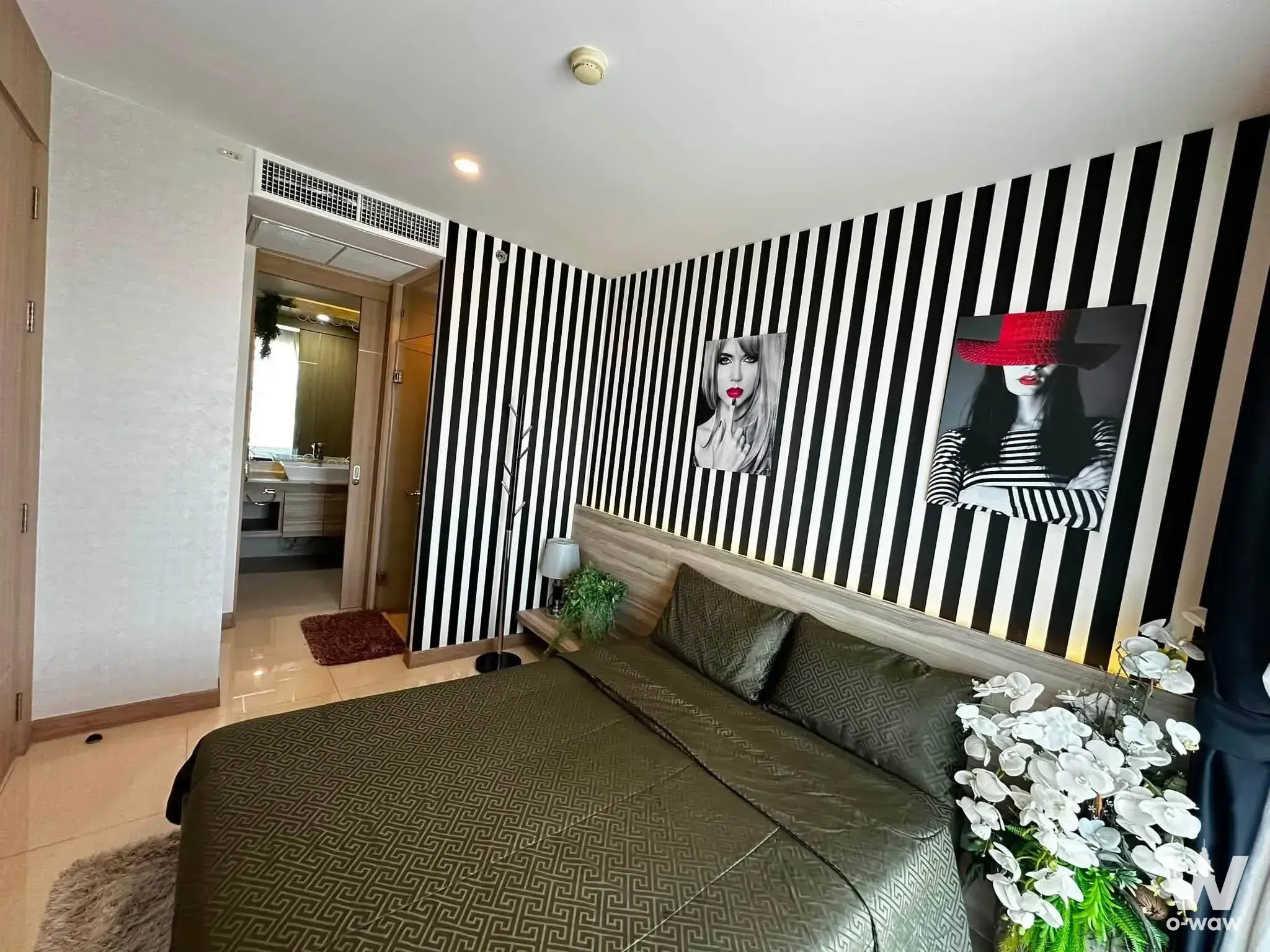 Furnished bedroom in The Riviera Jomtien with olive-green bedding and bold black-and-white striped accent wall