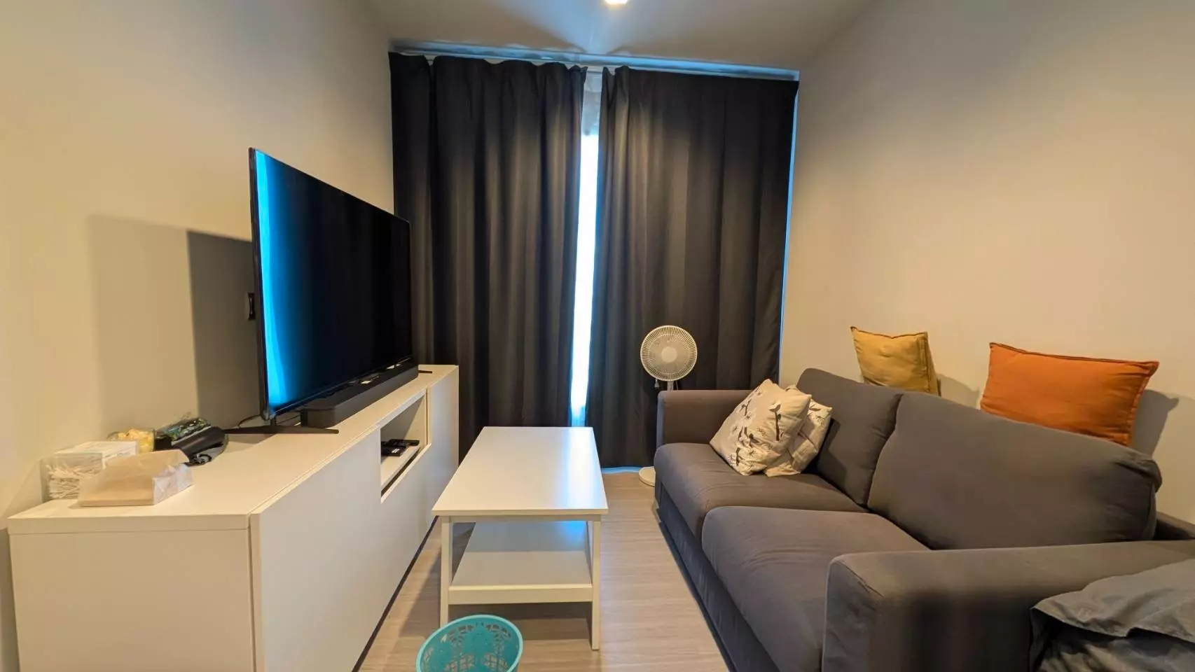 Living room featuring a dark grey sofa and white media console in this 1-bed condo for rent at Life Asoke Rama 9