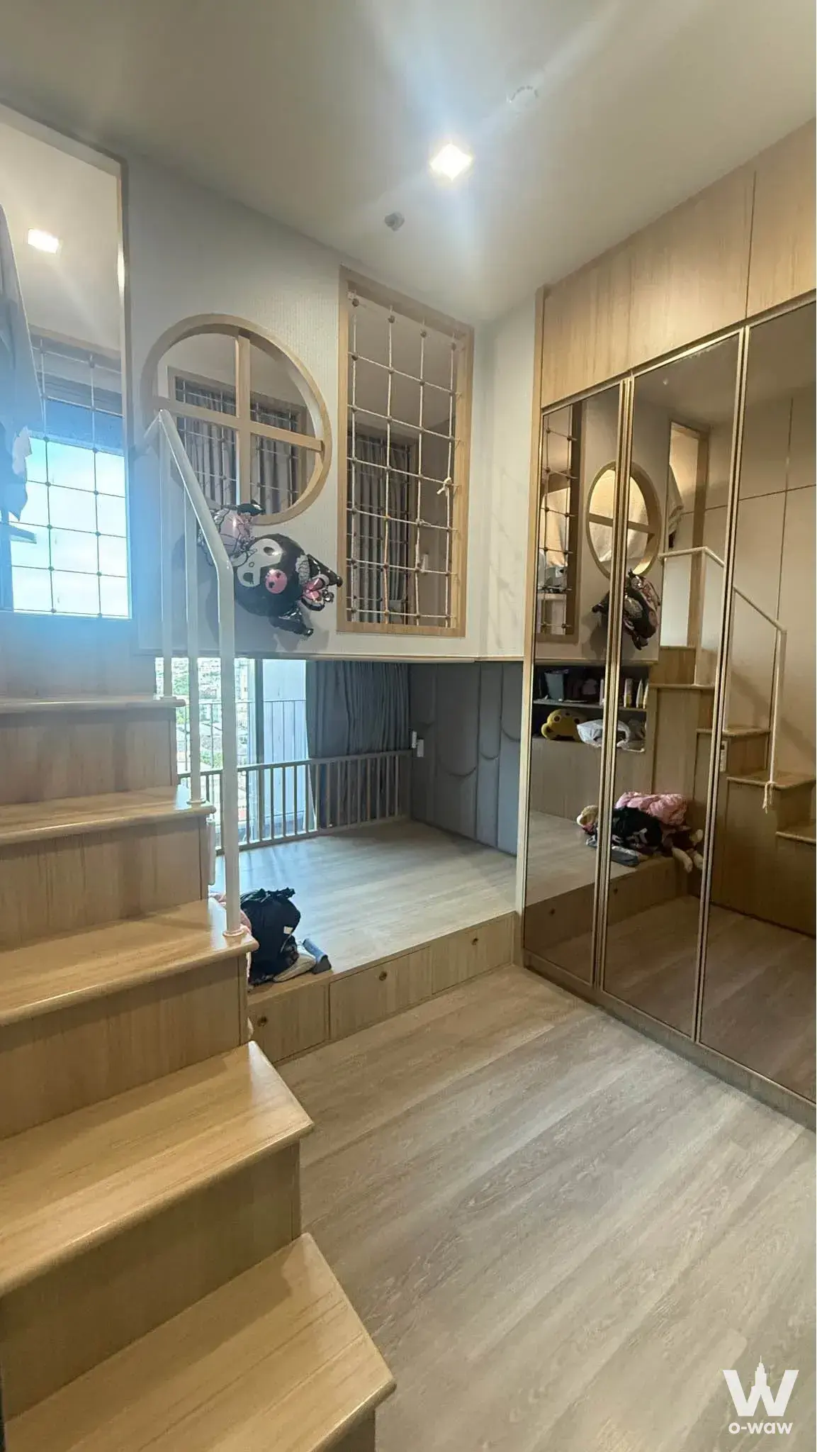Kids bedroom loft in Rhythm Charoenkrung with light-wood stairs, grey sleeping platform, and mirrored wardrobe