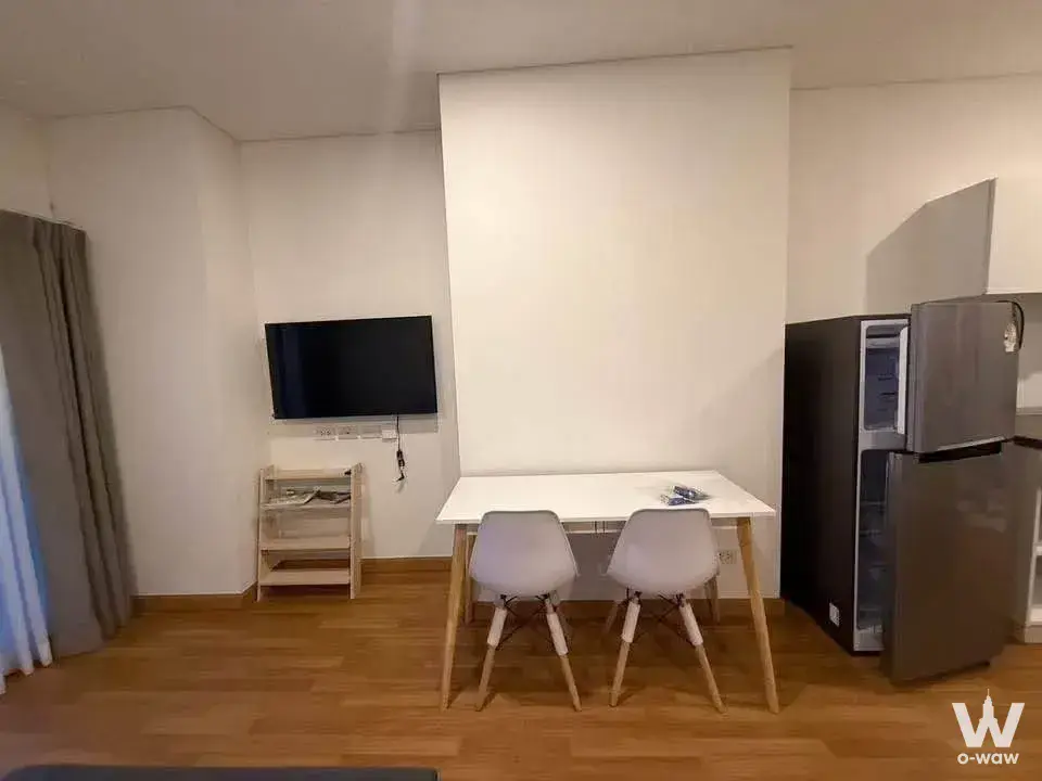 Bright living and dining area in a Lumpini Place Rama 3 condo with white table and grey chairs