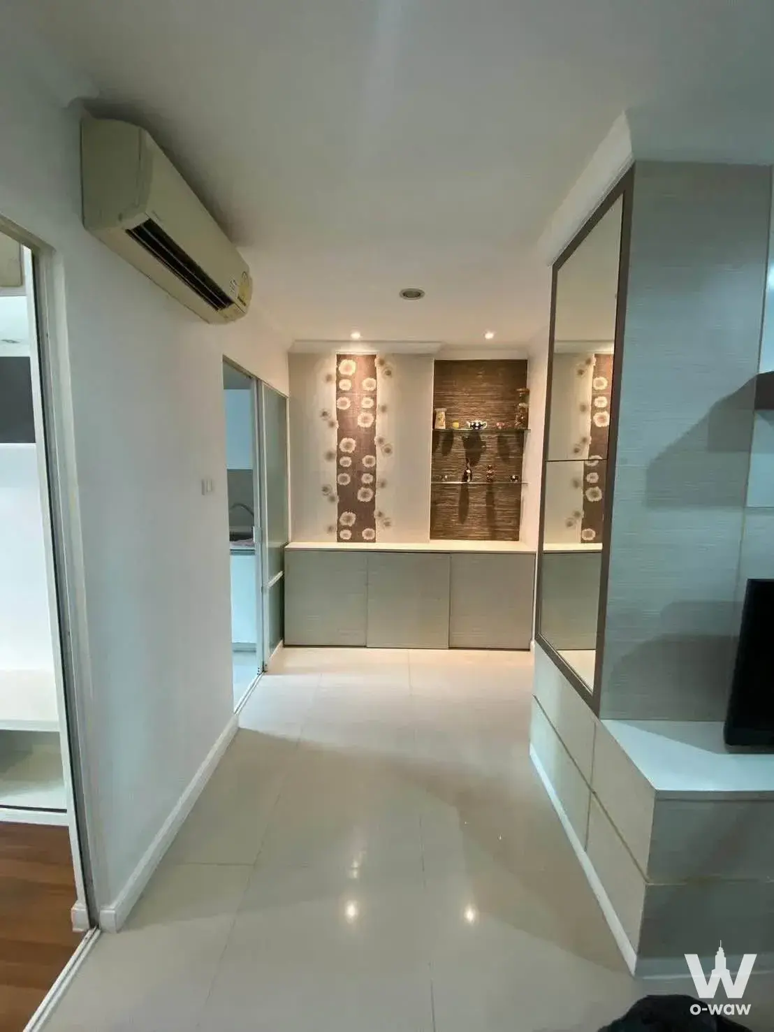 Condo hallway with beige tile, built-in cabinetry, and glass door at Lumpini Place Rama 8