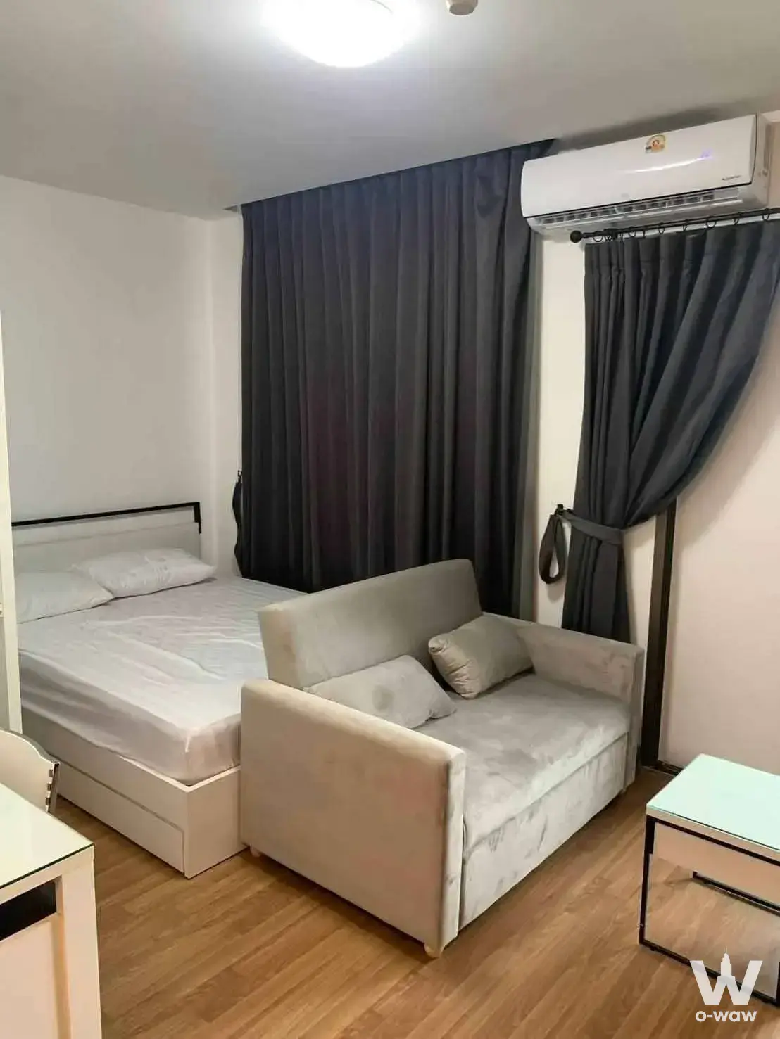 Modern bedroom featuring a queen bed and beige sofa in this furnished 1-bed condo for rent at Ideo Mix Sukhumvit 103