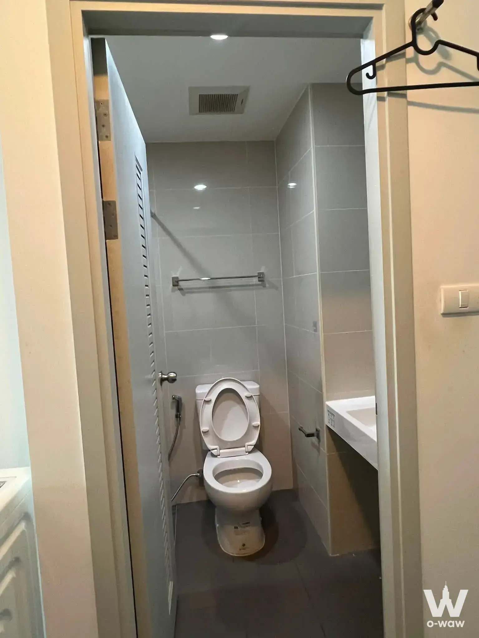 Compact modern bathroom in A Space Condominium rental with grey tiles, handheld bidet, and neutral tones
