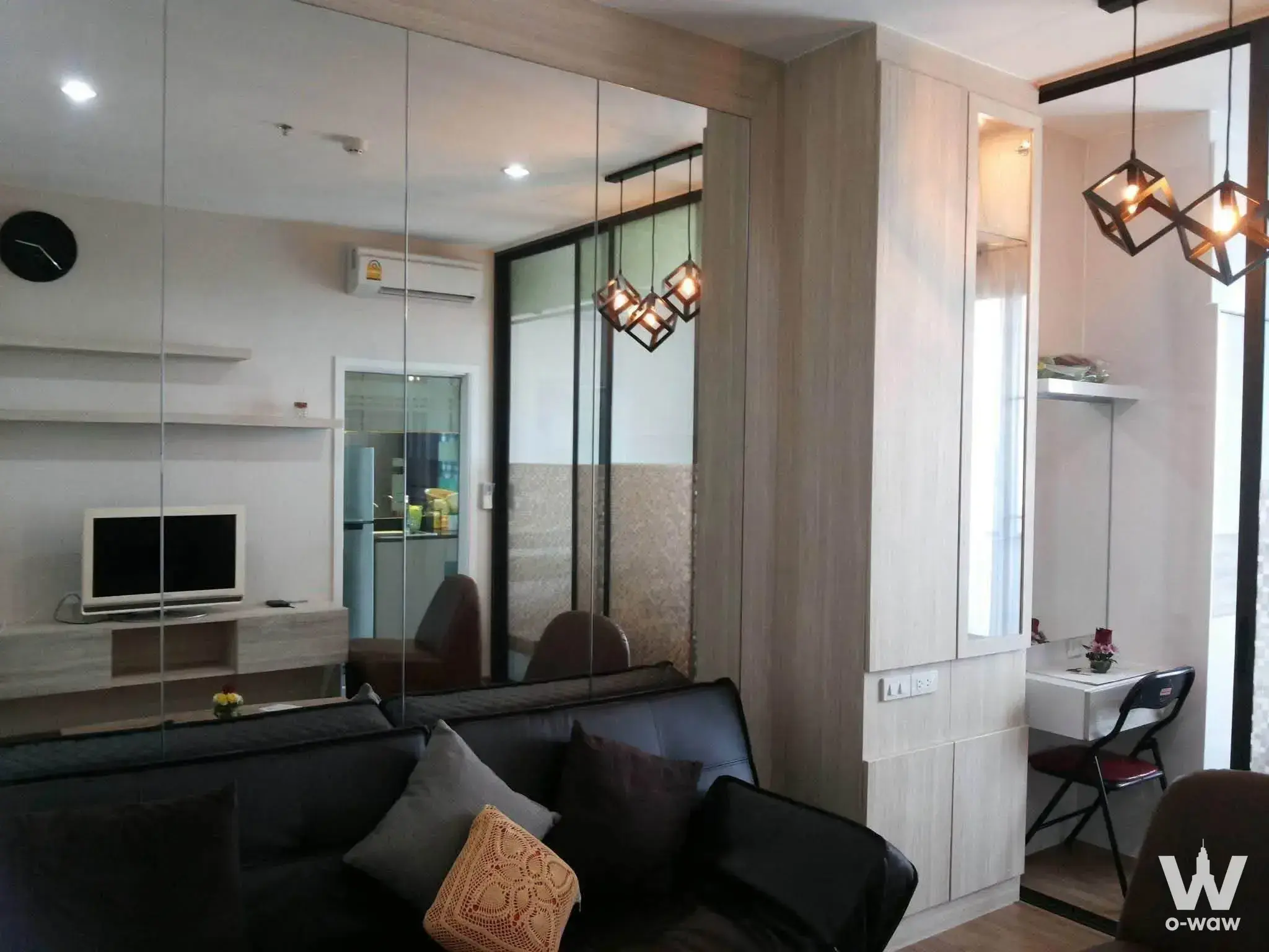 The Tree Rio Bang-Aor living room with dark leather sofa, mirrored walls, and warm pendant lighting