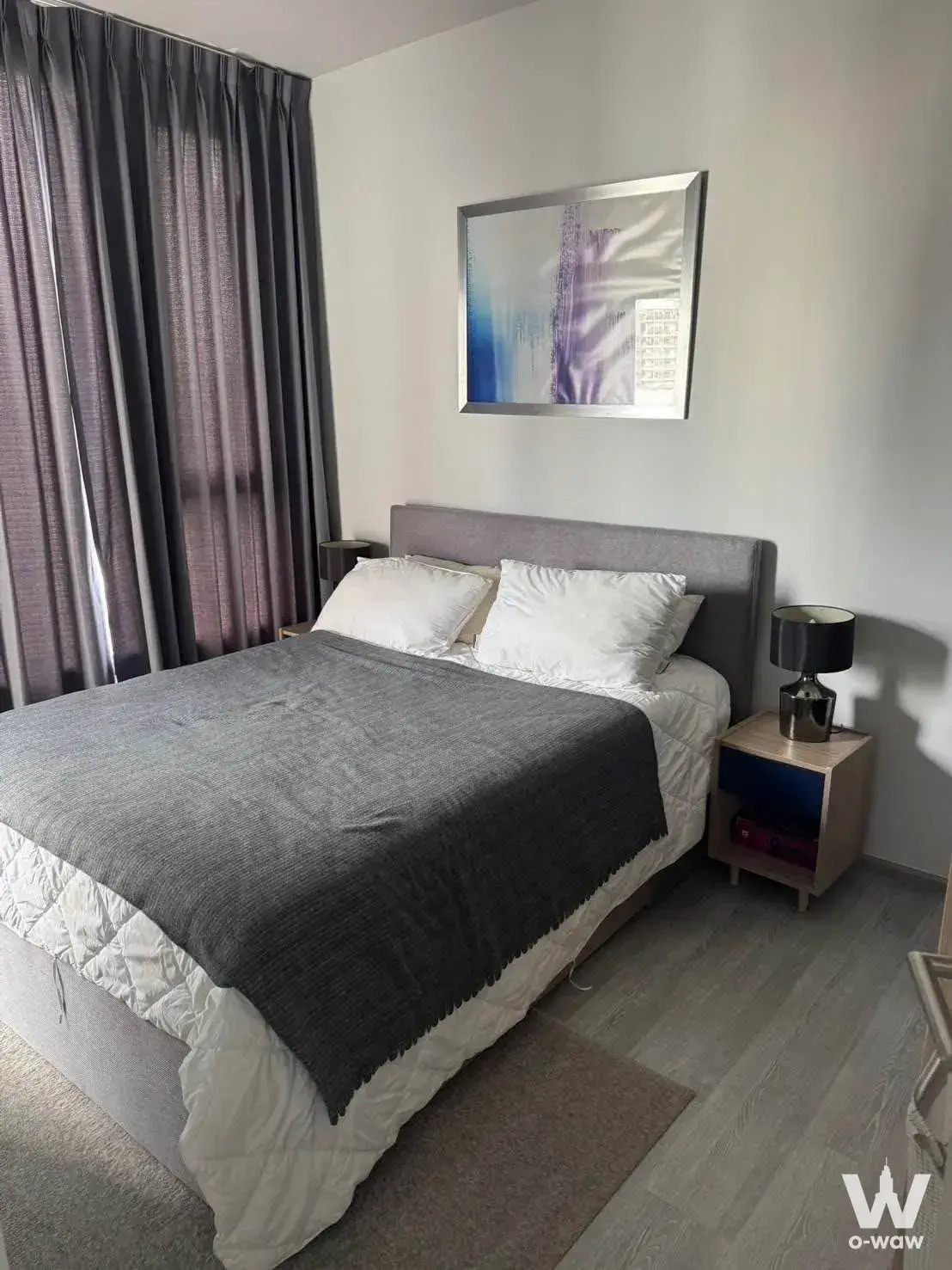Queen bed with grey headboard and abstract art in a 1-bed condo for rent at XT Ekkamai