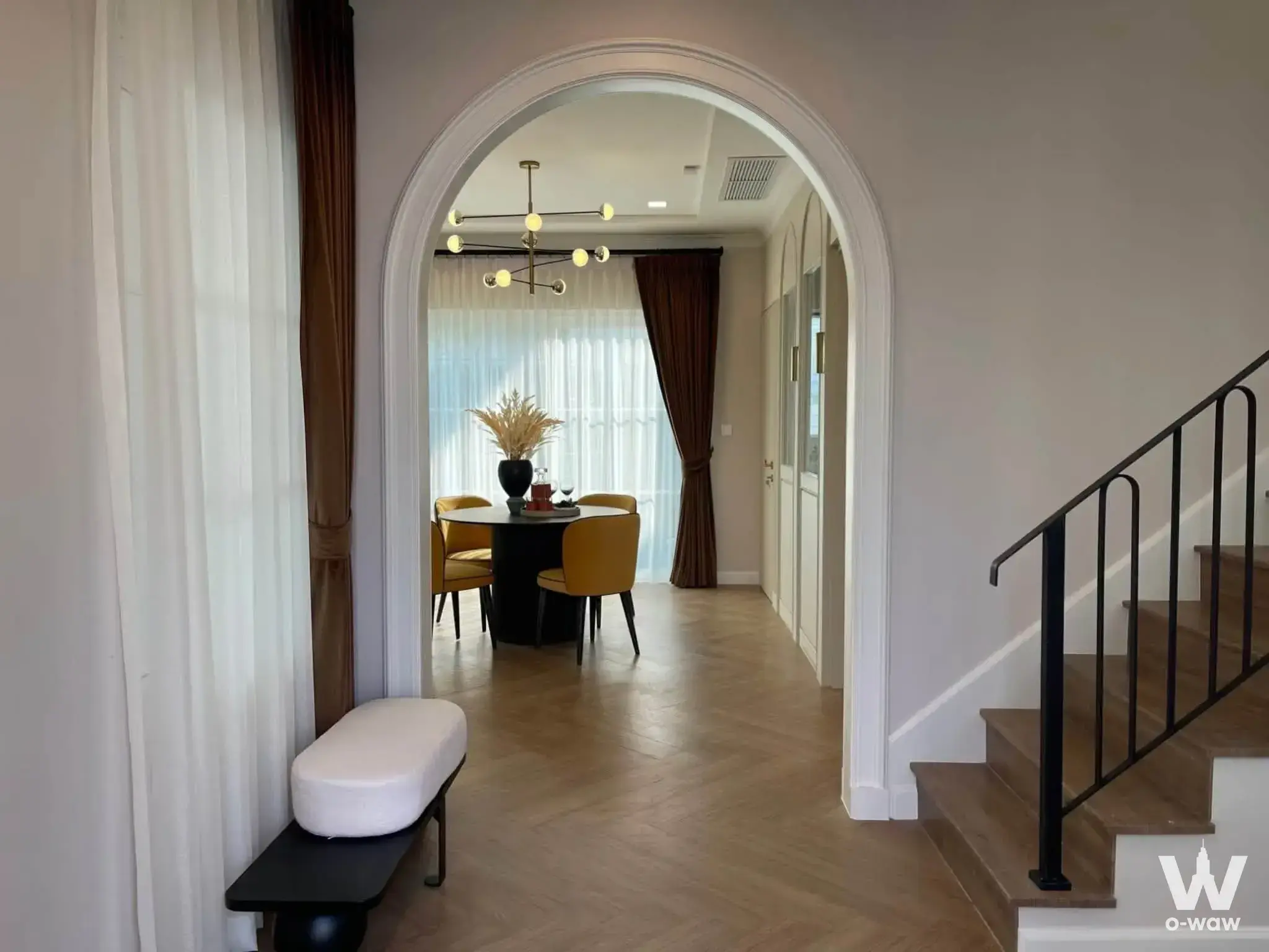 Hallway in Chaiyapruek Bangna house featuring herringbone floors and arched entry to dining area