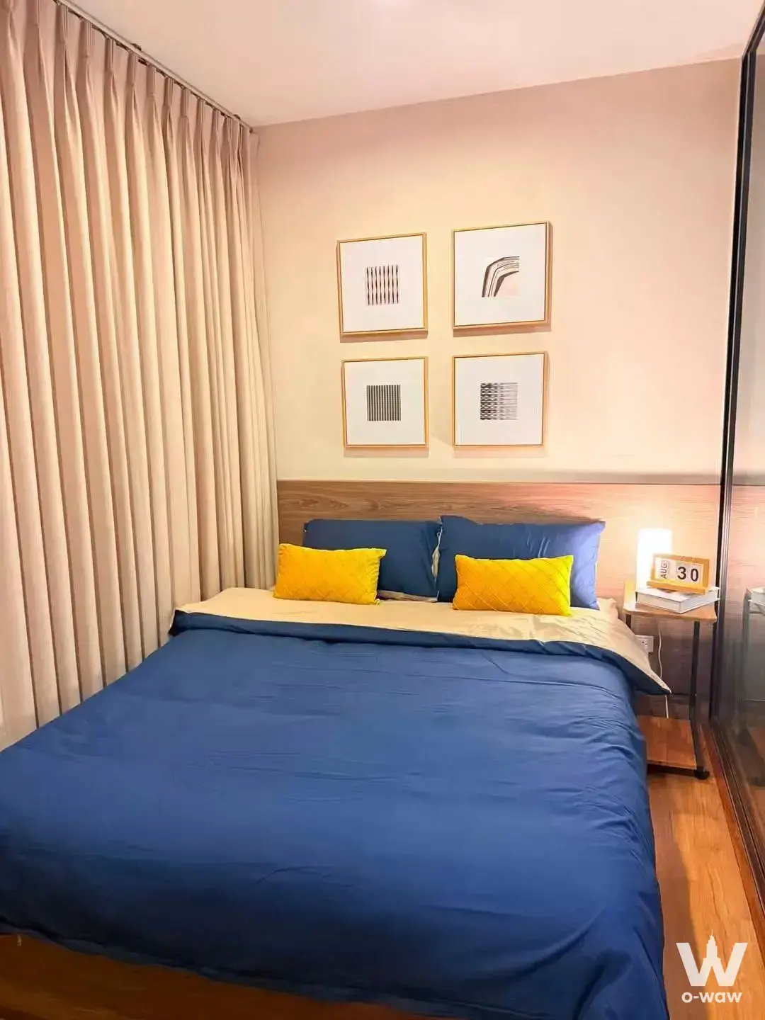 Furnished bedroom in The Tree Rio Bang-Aor condo showing a navy bed, gold-framed art, and warm ambient lighting