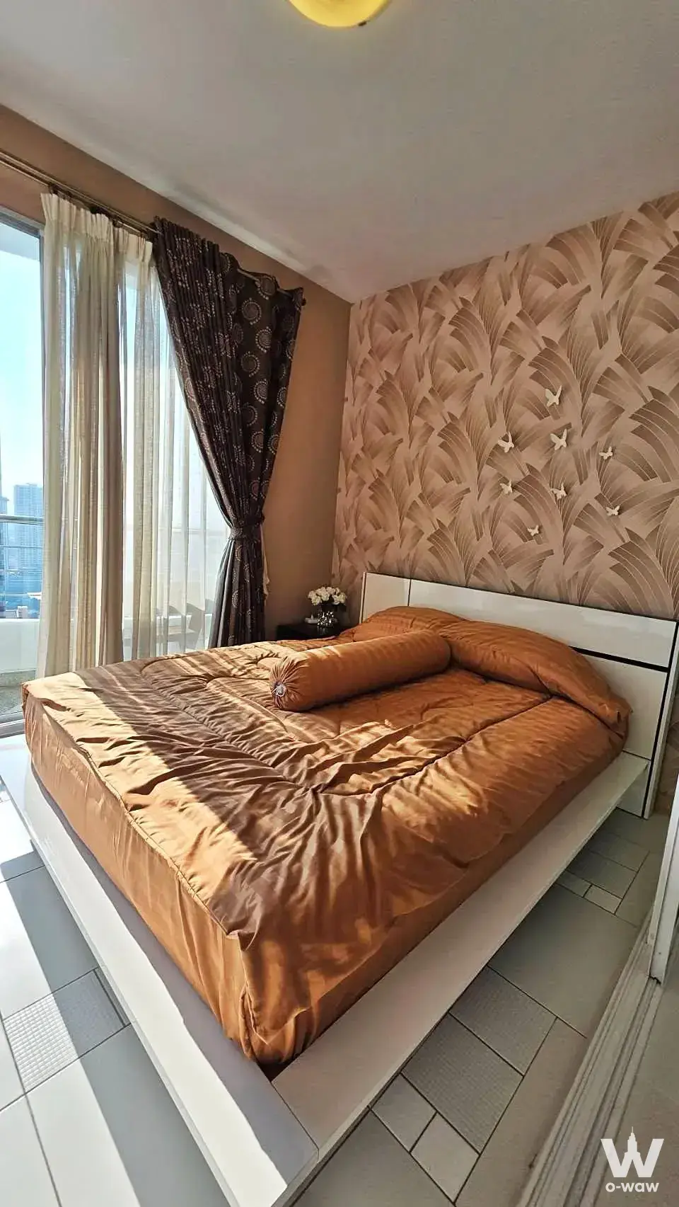 Bedroom in a Supalai River Place unit with burnt orange bedding and high-floor city skyline view