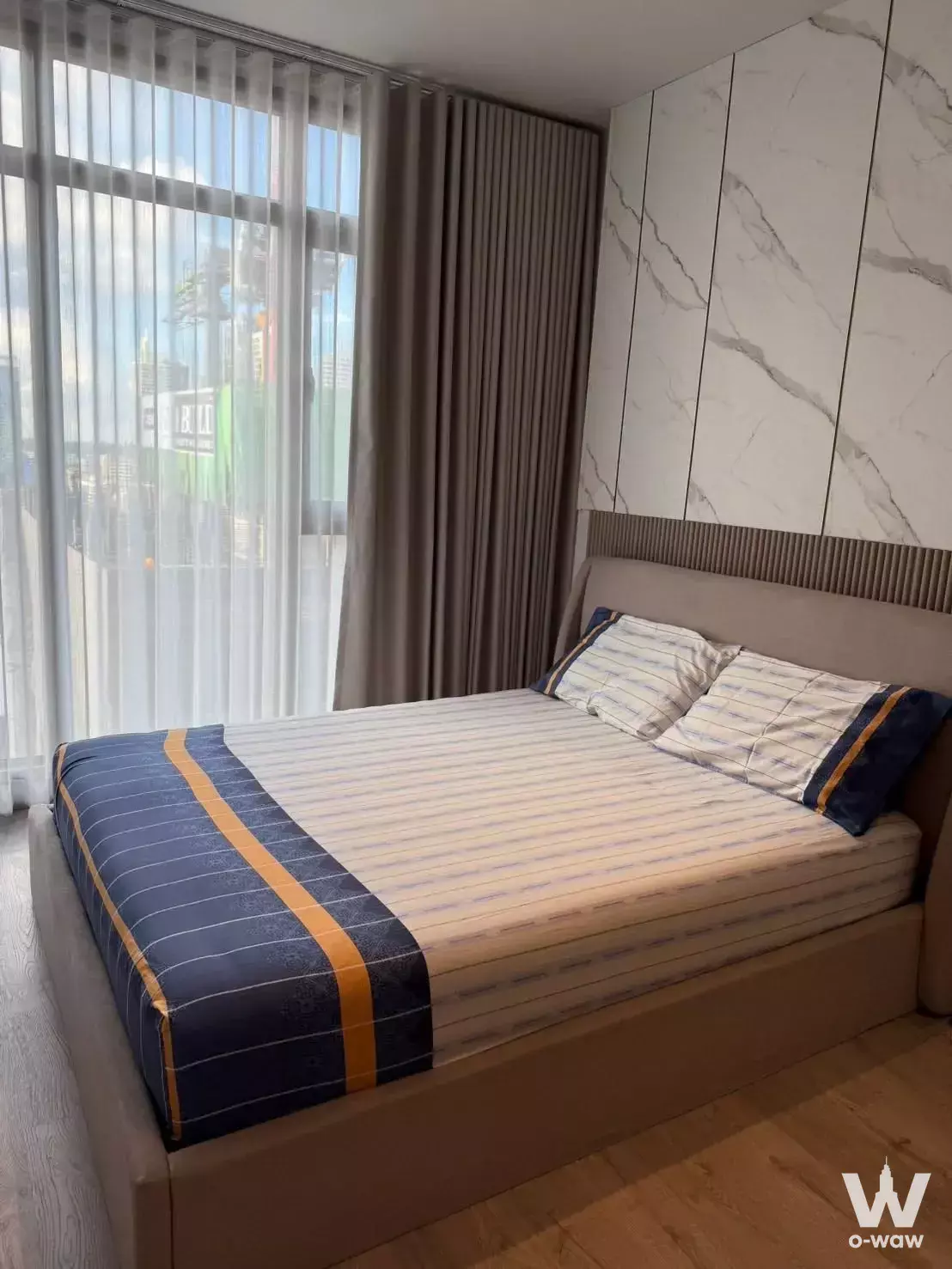 Rhythm Ekkamai Estate bedroom with marble feature wall, wood slat headboard, and city view