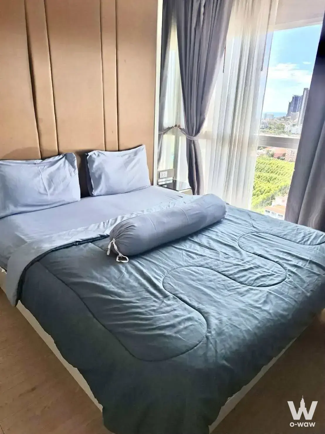 Queen bed with beige headboard and city view in this 1-bed La Santir condo for rent