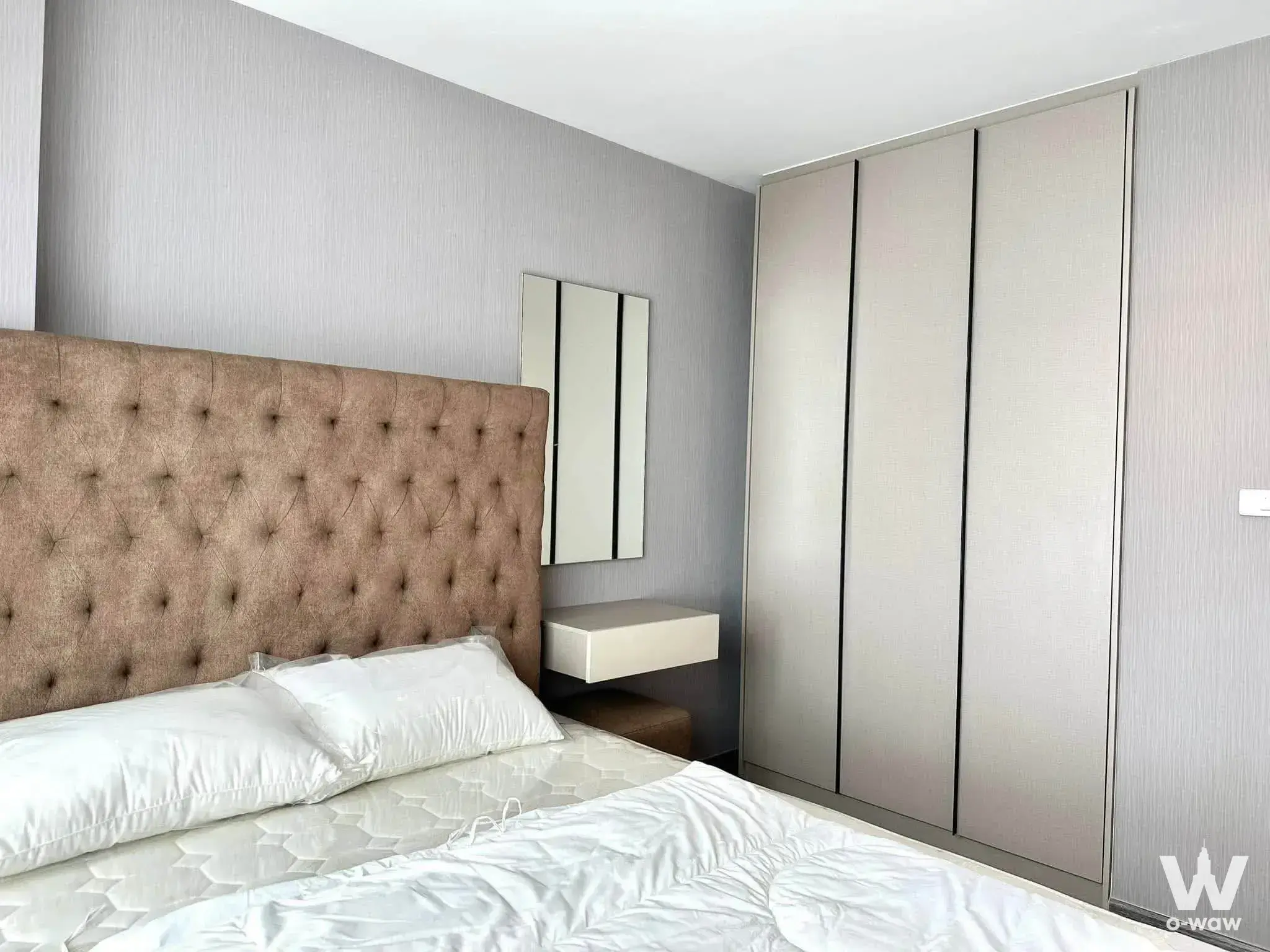 Master bedroom with tufted headboard and built-in wardrobe in Ideo Sukhumvit 93