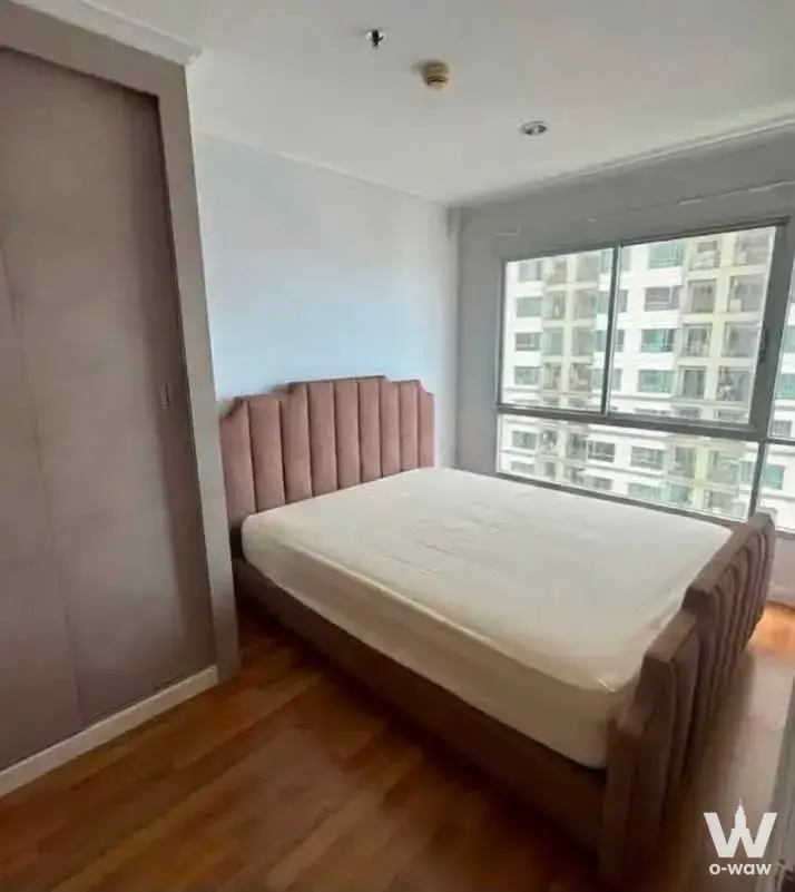 Bedroom in Lumpini Park Riverside Rama 3 featuring a rose tufted bed and floor-to-ceiling window with high-rise view