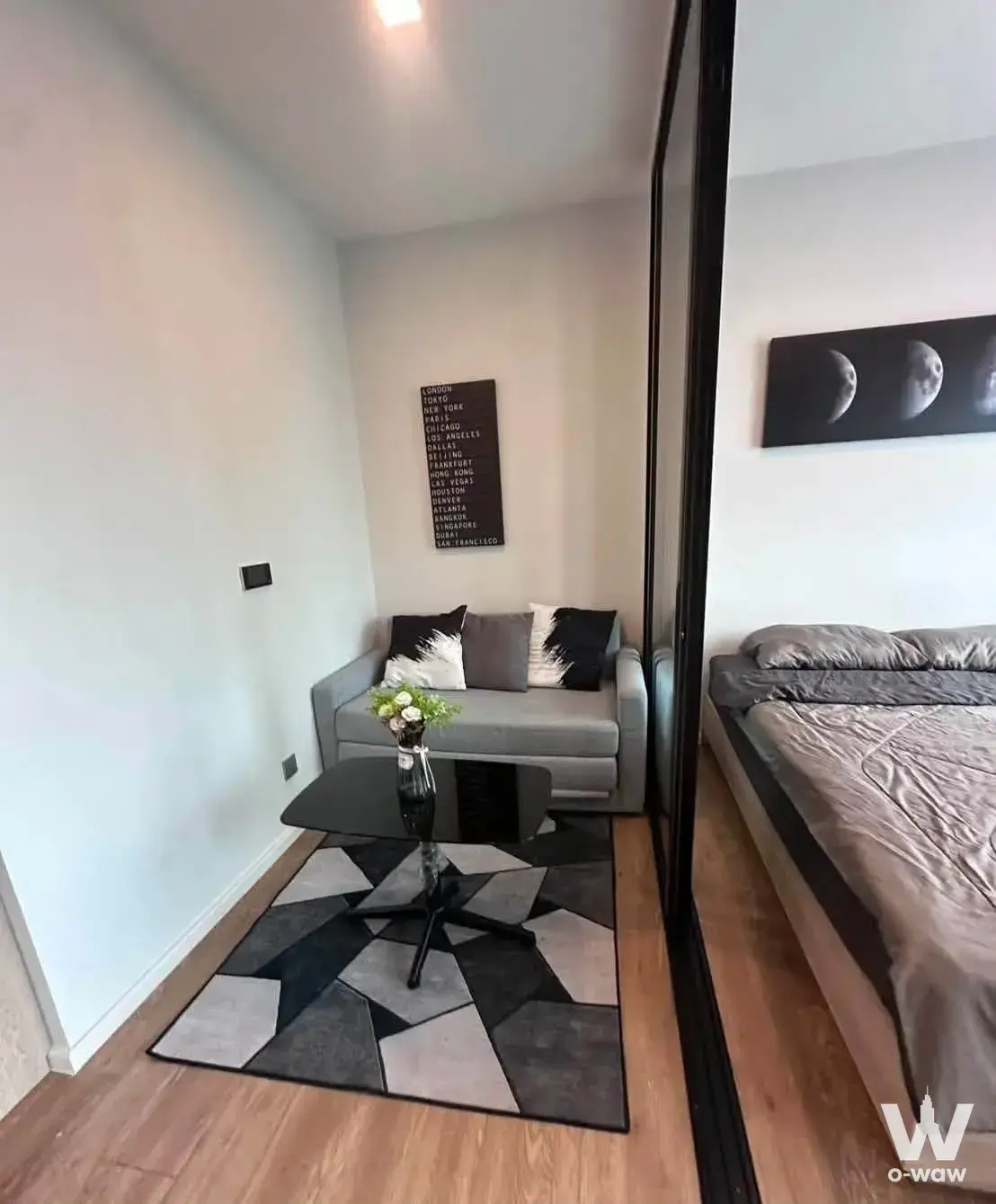 Open-plan studio in Modiz Sukhumvit 50 condo with grey sofa and partitioned sleeping area
