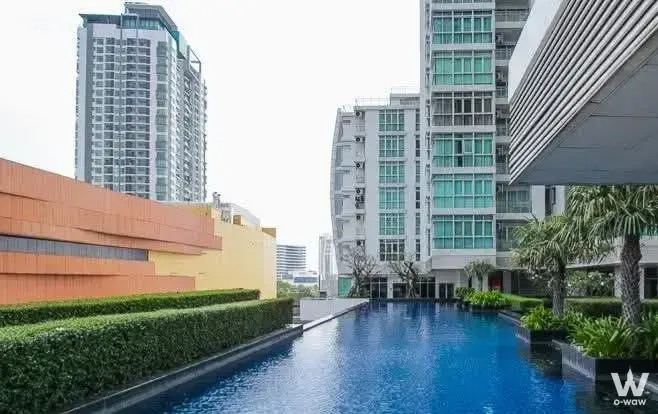 Rectangular lap pool at Nusasiri Grand Condo surrounded by palms and high-rise buildings