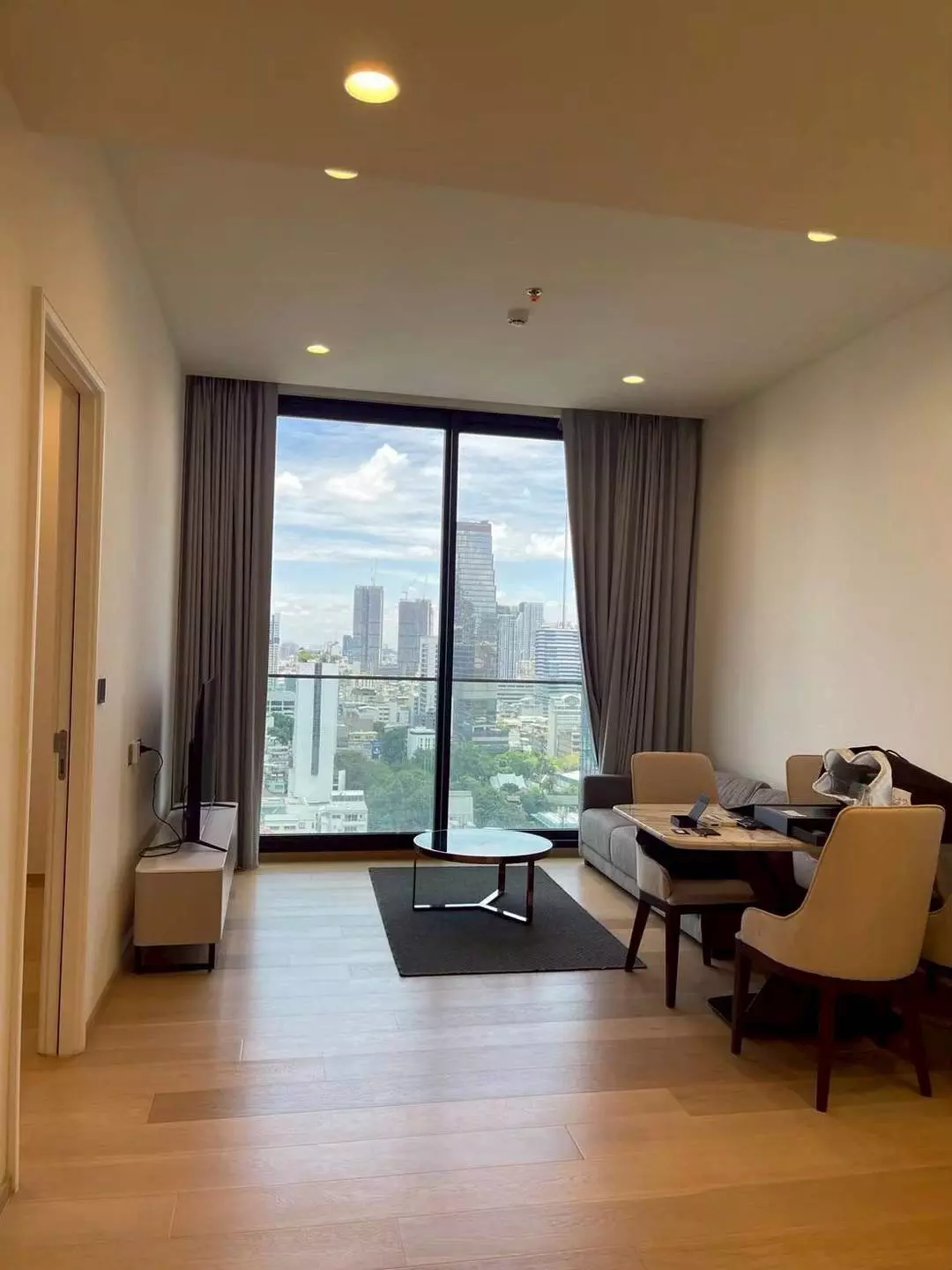Bright dining area in ANIL Sathon 12 condo featuring wood table and city skyline view