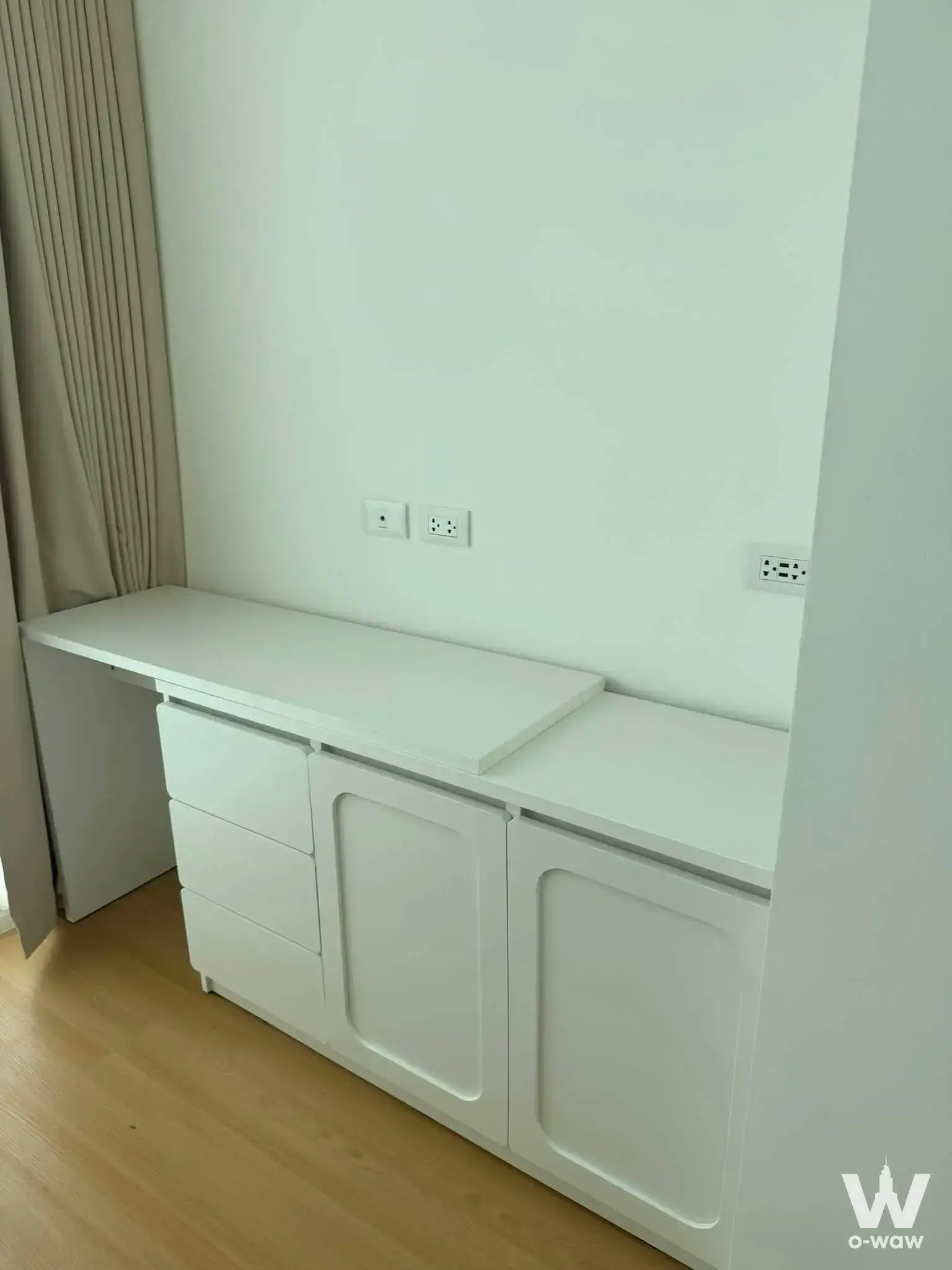 Built-in white cabinetry and light oak flooring in a minimalist Cerocco Bangna 36 condo