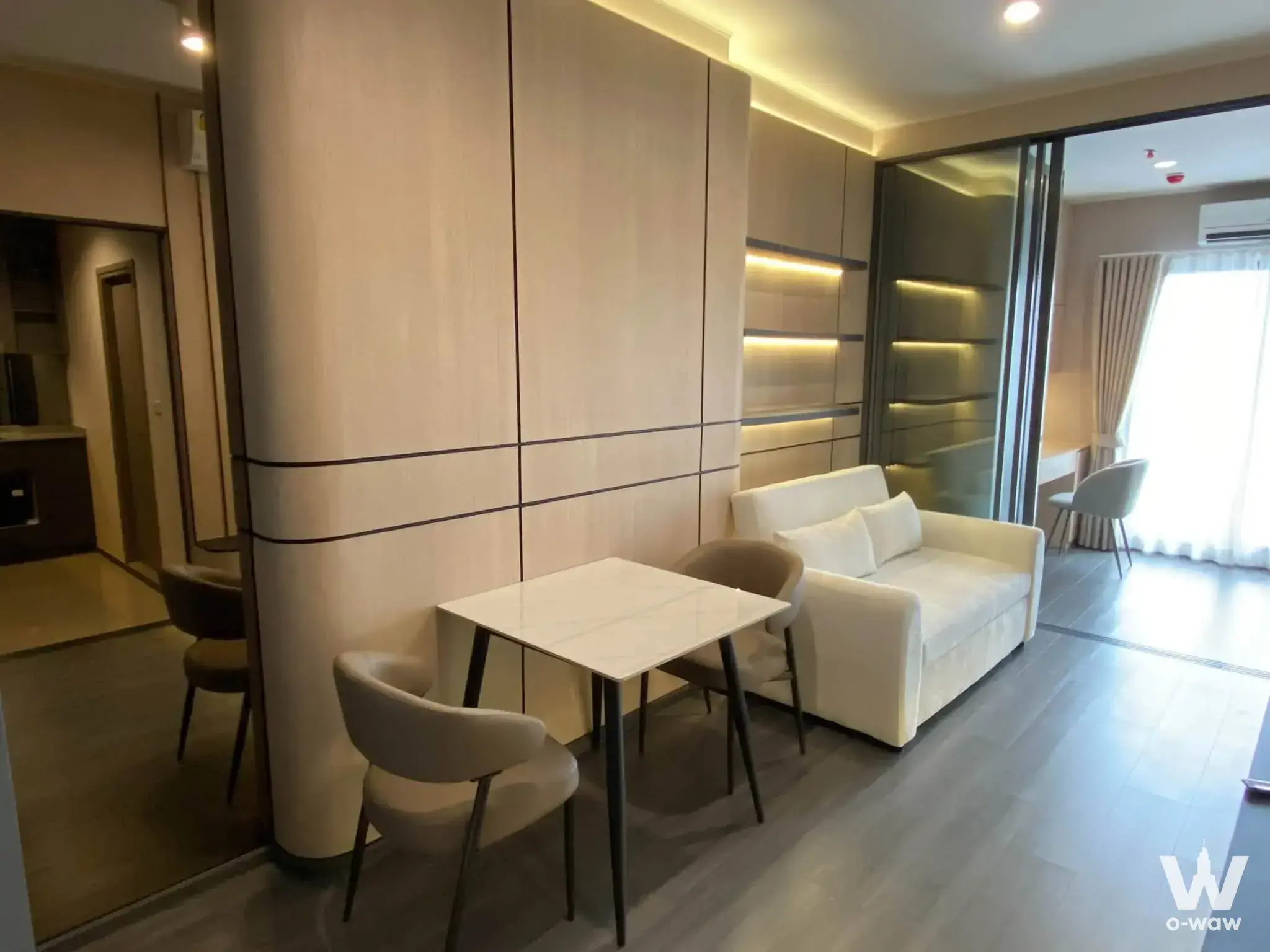 Bright living room in a Life Rama 4 condo with light wood walls and a marble dining table