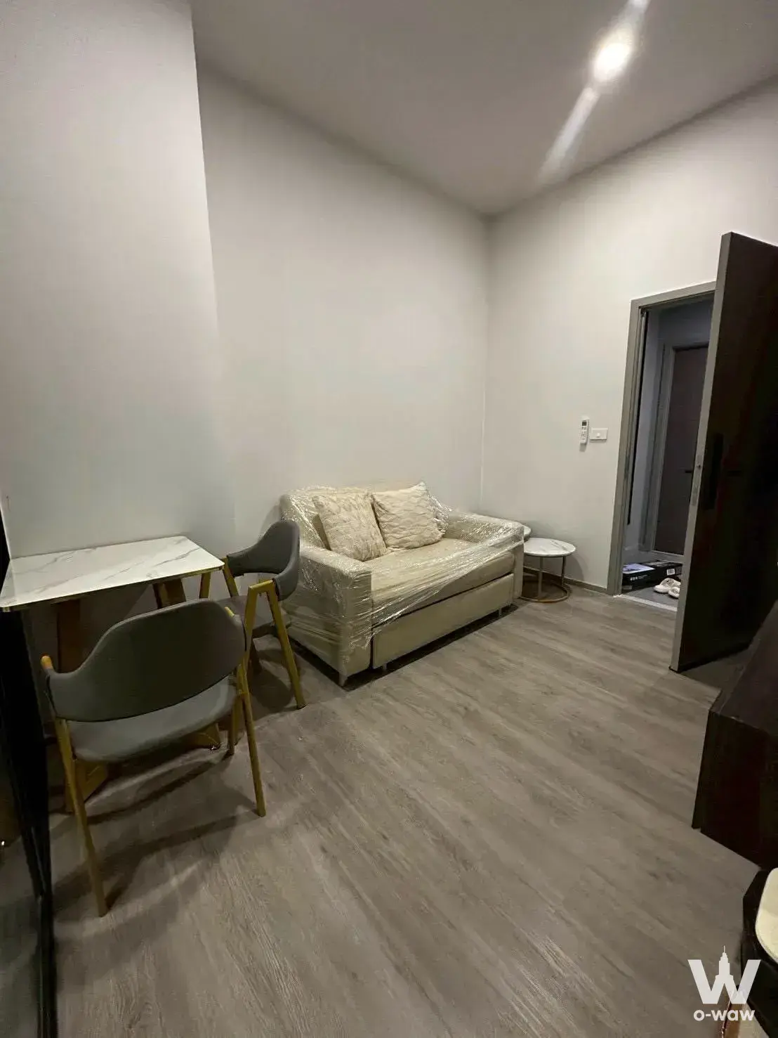 Studio living room with beige sofa and marble dining table for 0-bed rent at Origin Plug & Play Ramintra