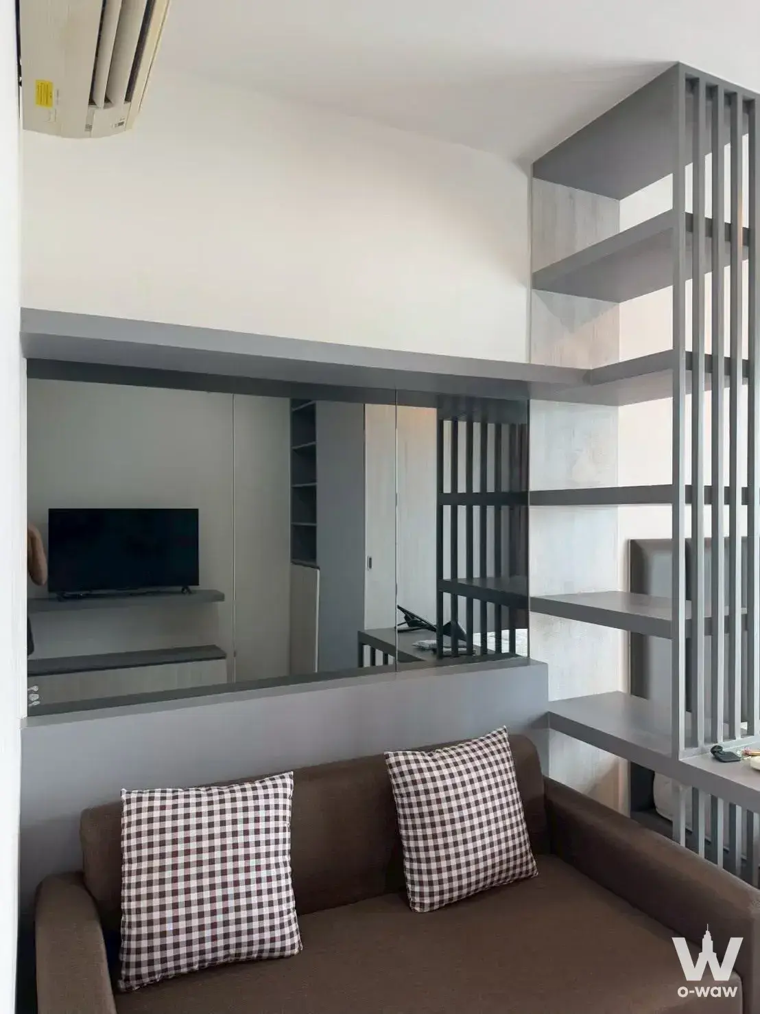 Living room corner with sofa and mirror reflecting TV in a 1-bed unit for rent at Ideo Mobi Sukhumvit Eastgate