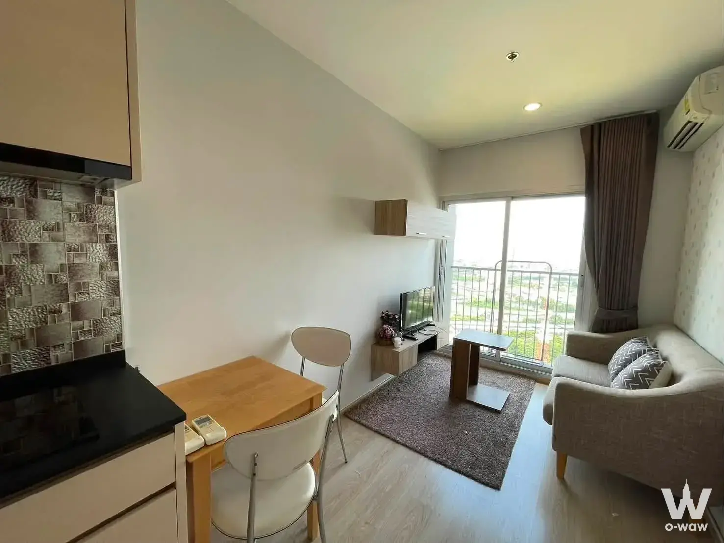 Furnished 1-bed studio for rent at Noble Revolve Ratchada 1 featuring a grey sofa and balcony view