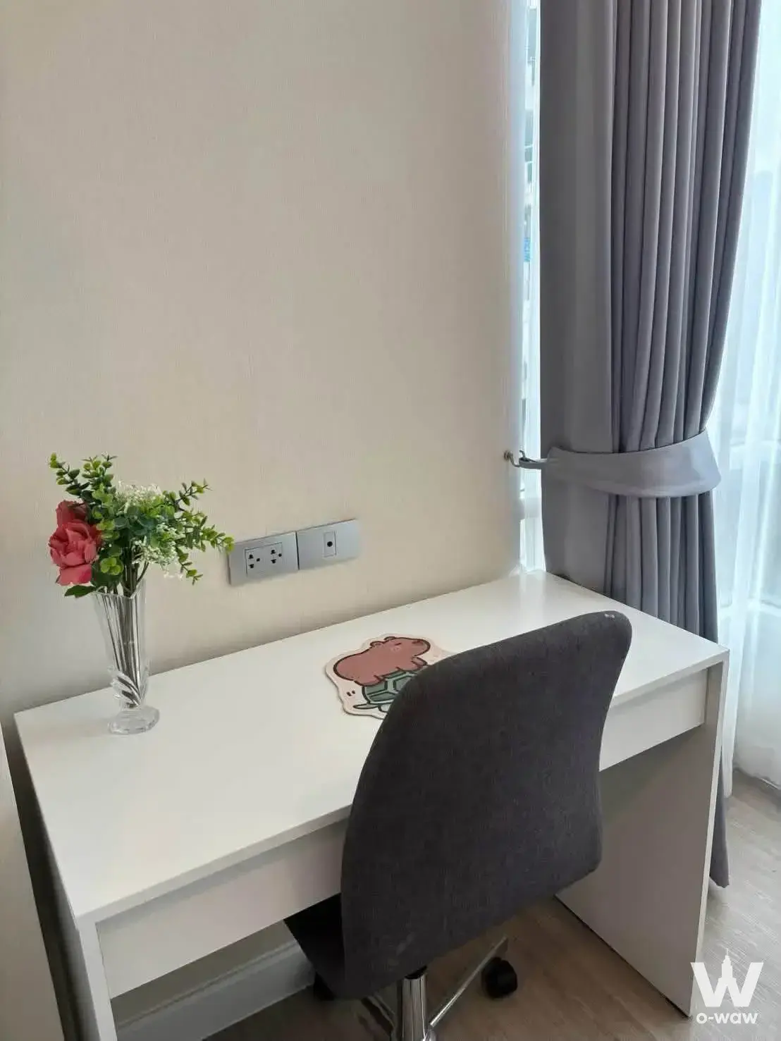 Home office corner in The Sky Sukhumvit condo near BTS Udom Suk with white desk, grey chair, and window view
