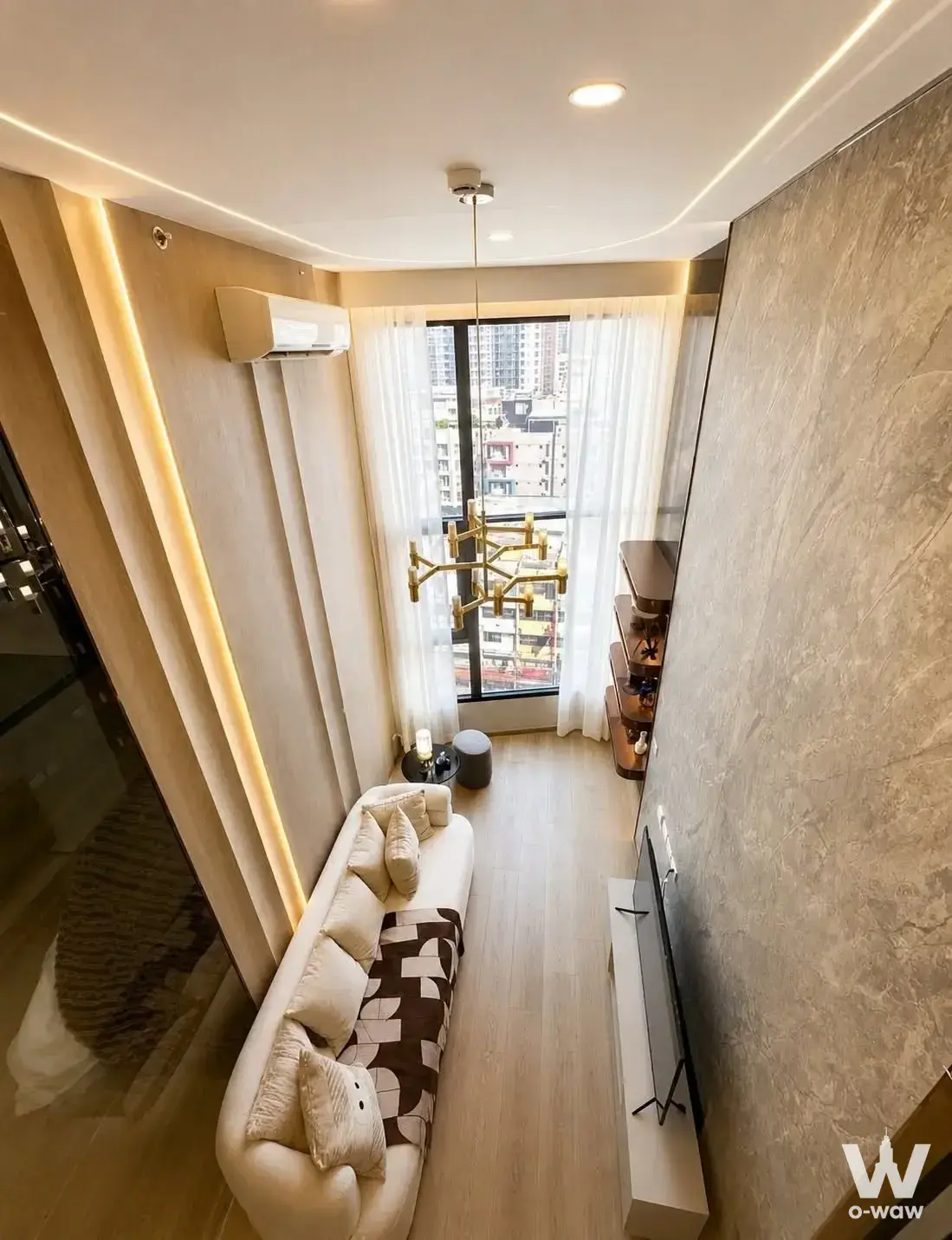 SOHO Bangkok Ratchada living room featuring cream curved sofa and textured stone accent wall
