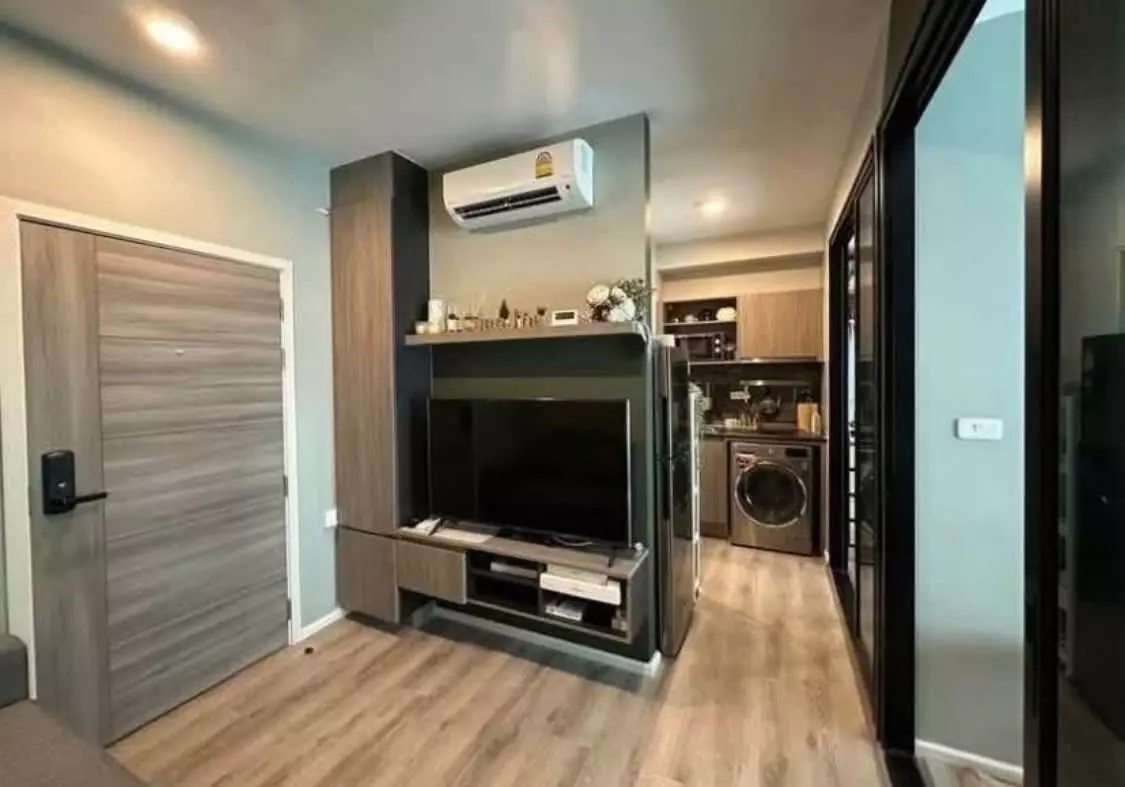 Living area of a Notting Hill Sukhumvit 105 condo featuring built-in media unit and smart lock door