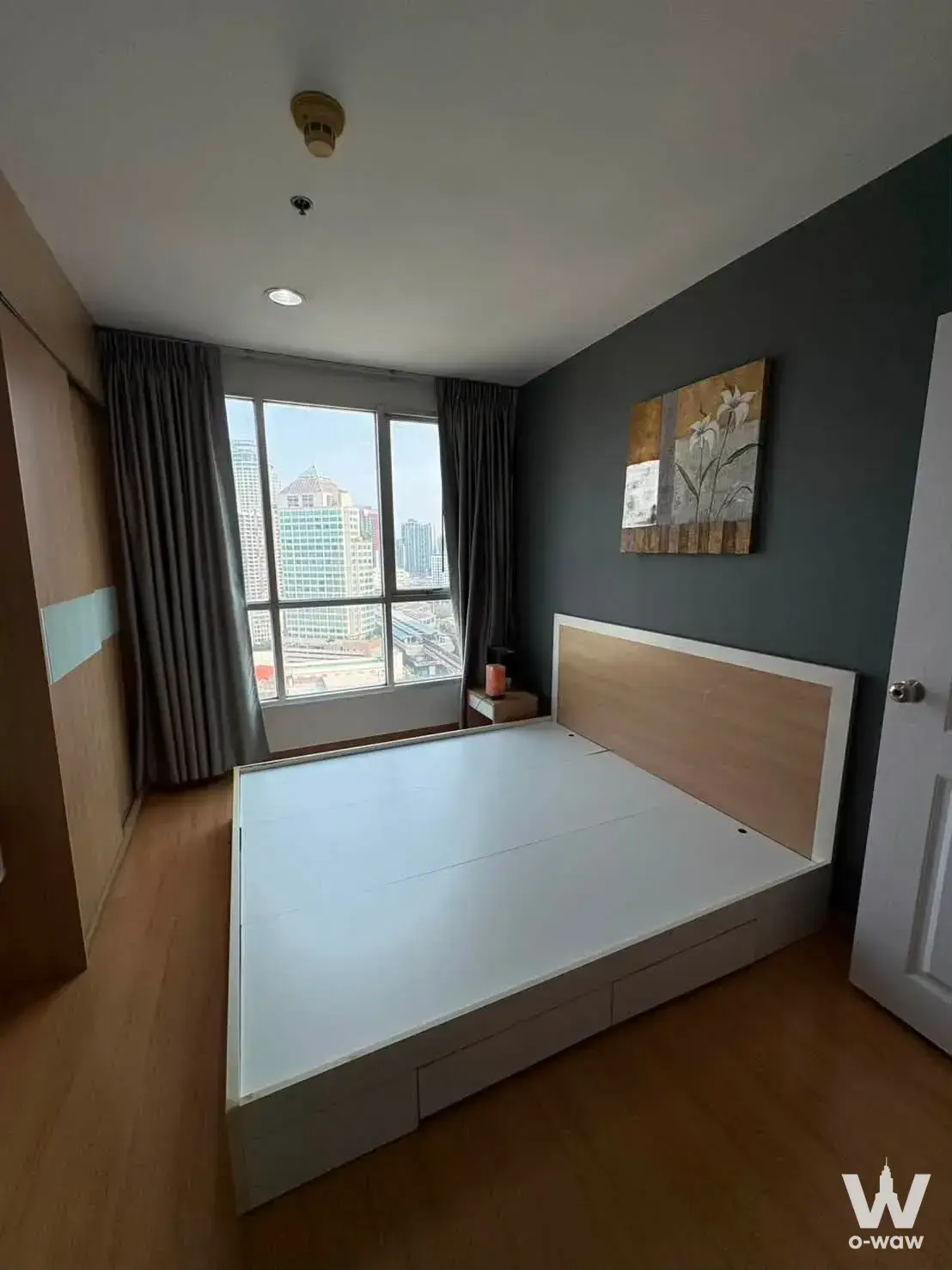 Bright bedroom in a Life Sukhumvit 62 rental with floor-to-ceiling city views and built-in oak storage