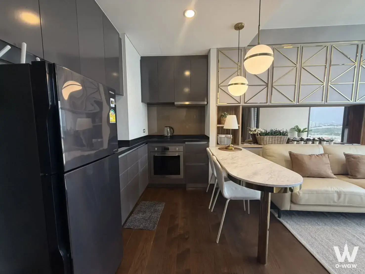 Kitchen living area in The Lumpini 24 with dark grey cabinets and marble-effect dining table