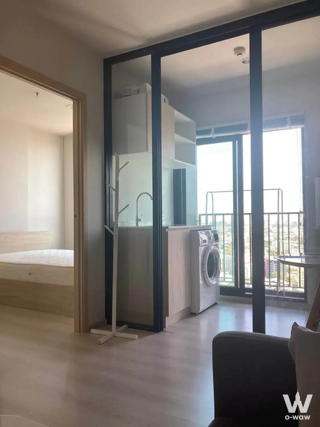 Compact studio with a glass partition and balcony skyline view in this 1-bed condo for rent at NUE Noble Ngamwongwan