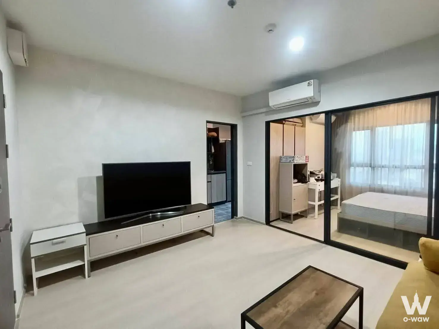 Open-plan living area in IDEO Sukhumvit 115 with a sliding glass partition separating the bedroom