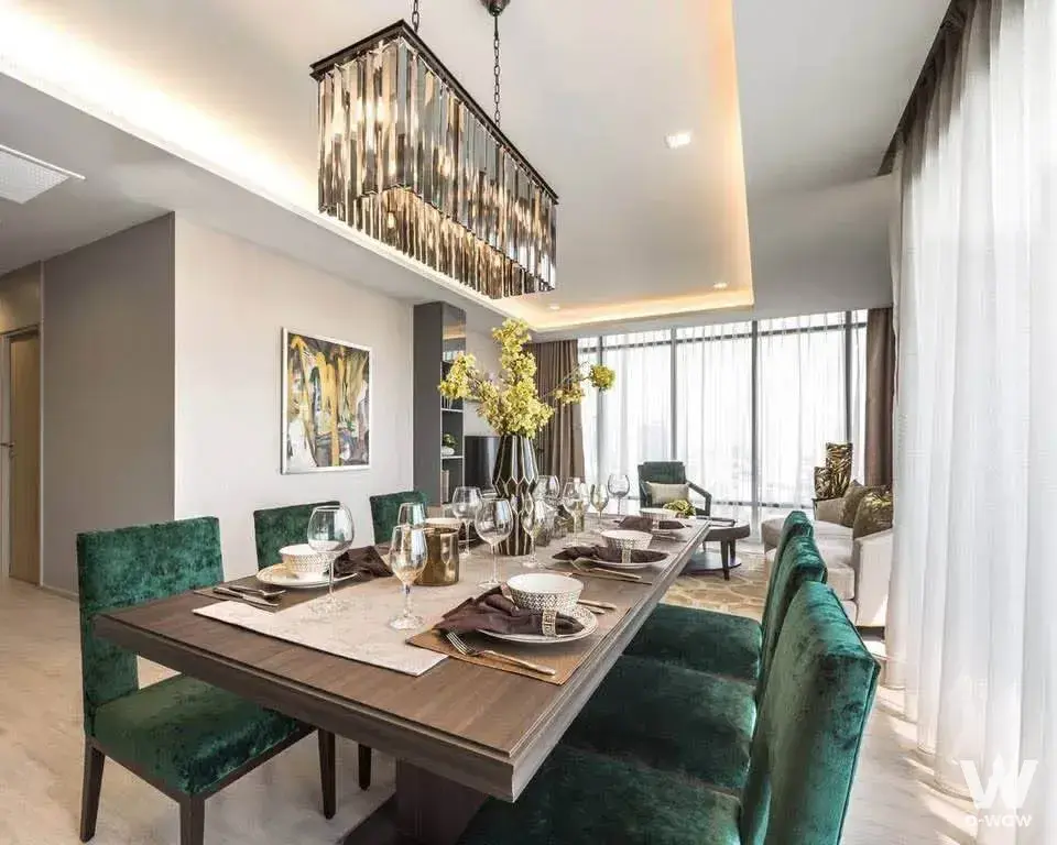 Dining room in M Thonglor 10 condo with dark wood table, emerald green velvet chairs, and crystal chandelier
