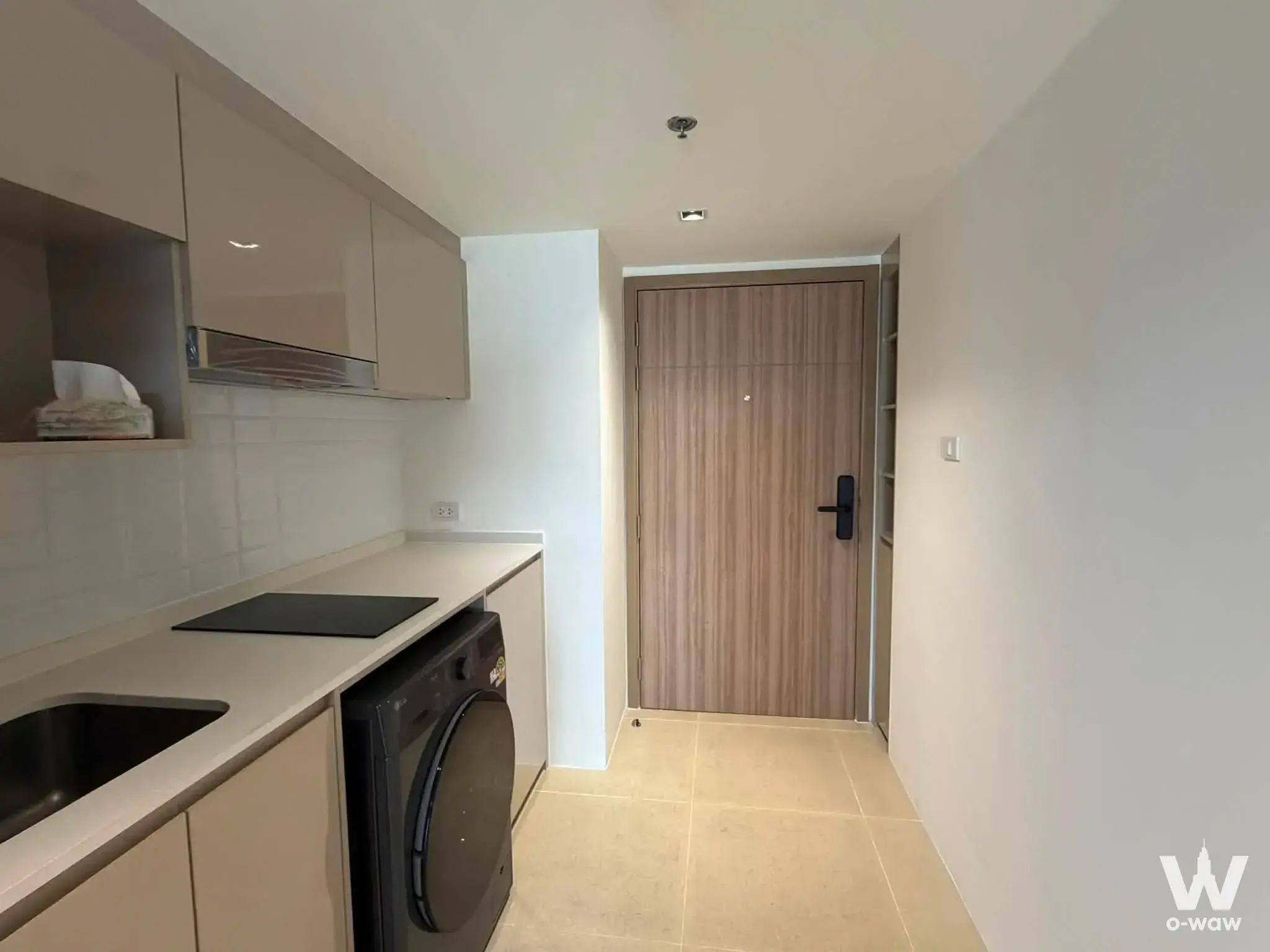 Compact kitchenette with beige cabinetry and integrated washing machine in 1-bed Na Reva Charoennakhon condo