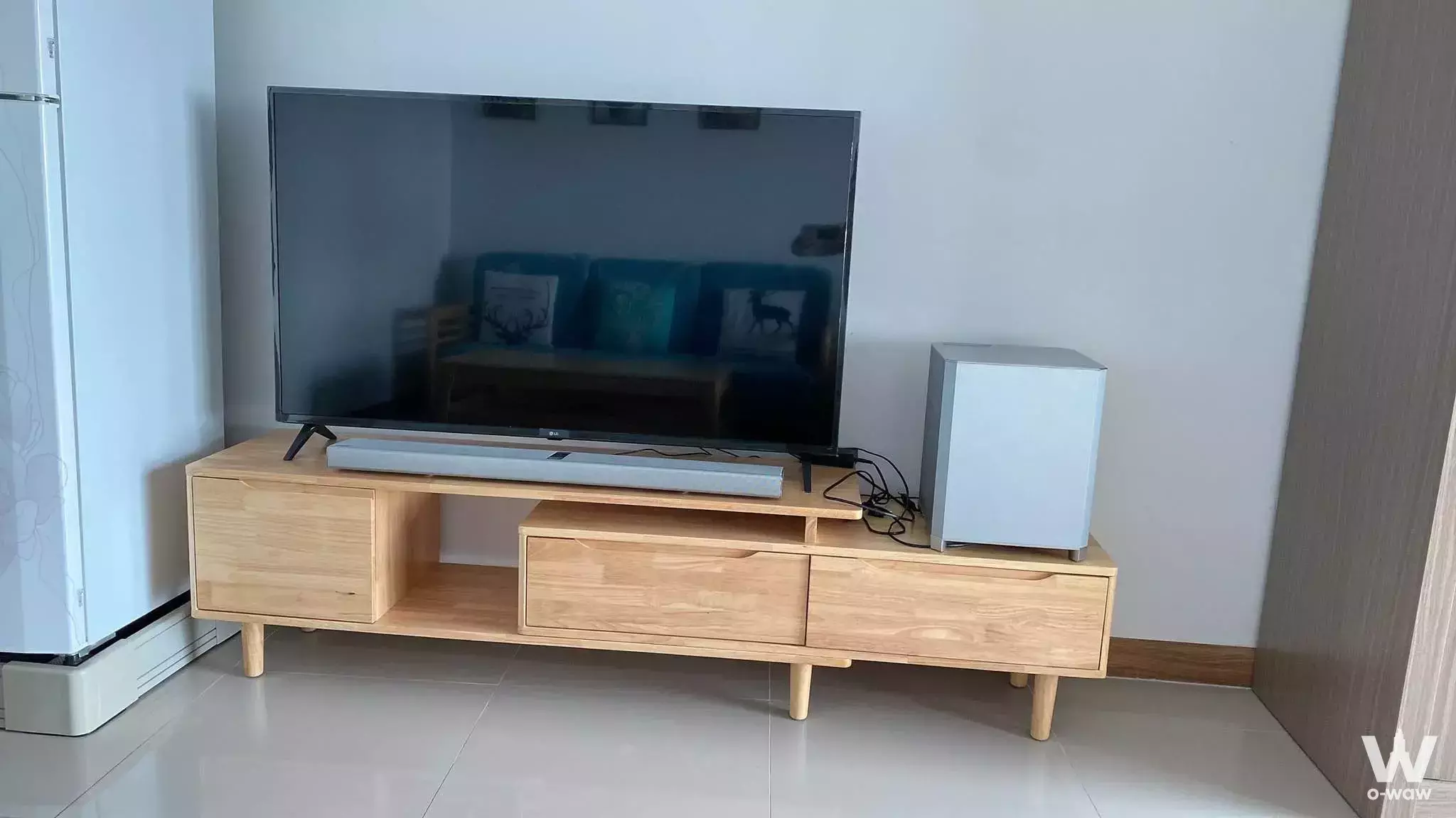 Living room in Supalai River Resort condo with mid-century TV console, flat-screen TV, and light-oak flooring