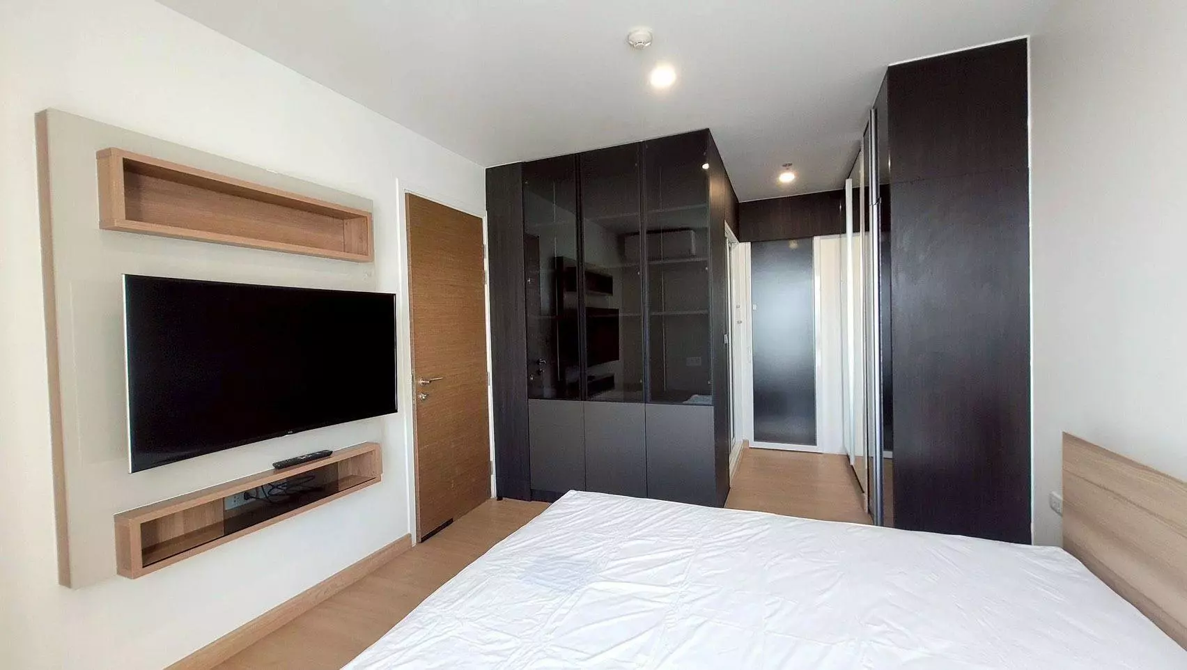 Master bedroom in RHYTHM Phahon-Ari featuring white linens and dark espresso wardrobe