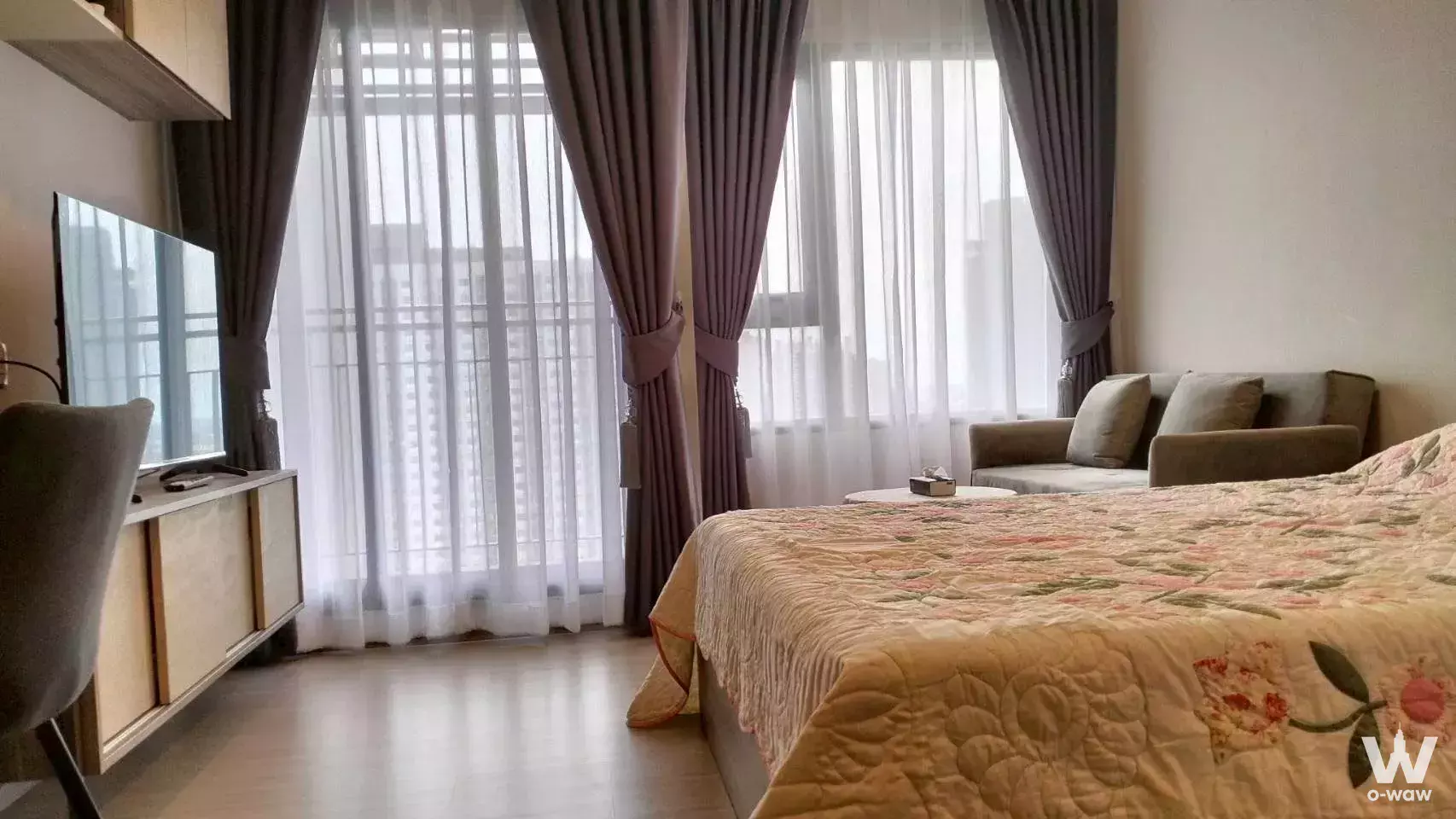 Bedroom in a 1-bed condo for rent at Life Sathorn Sierra with floral comforter and large window views