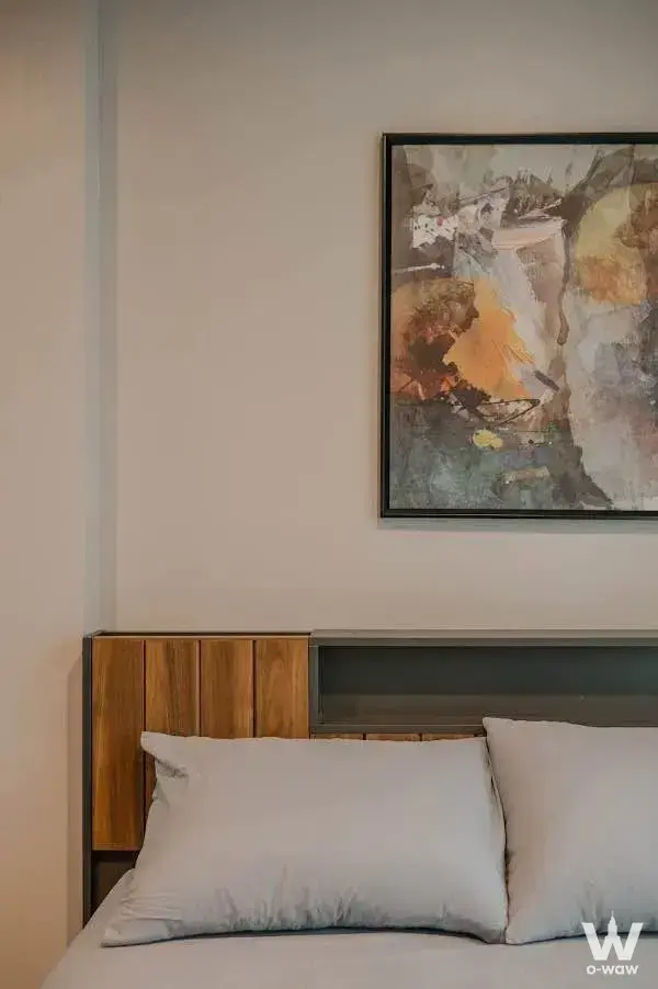 Queen bed with wood slat headboard and abstract art in a THE BASE Sukhumvit 77 bedroom