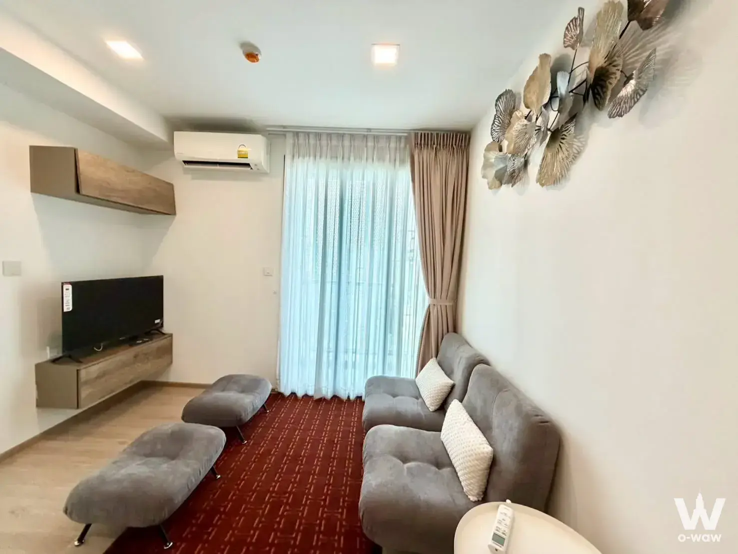 Modern living room in Taka Haus 1-bed condo with grey sofa and red geometric rug