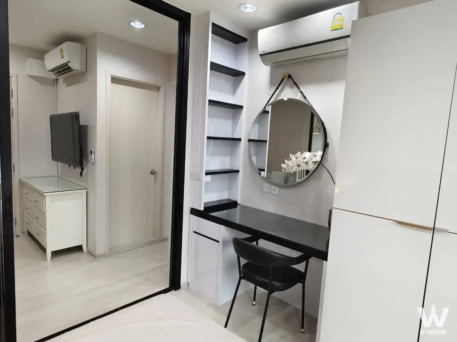 Life Asoke 1-bed condo bedroom with minimalist white decor, black desk, and tall shelving