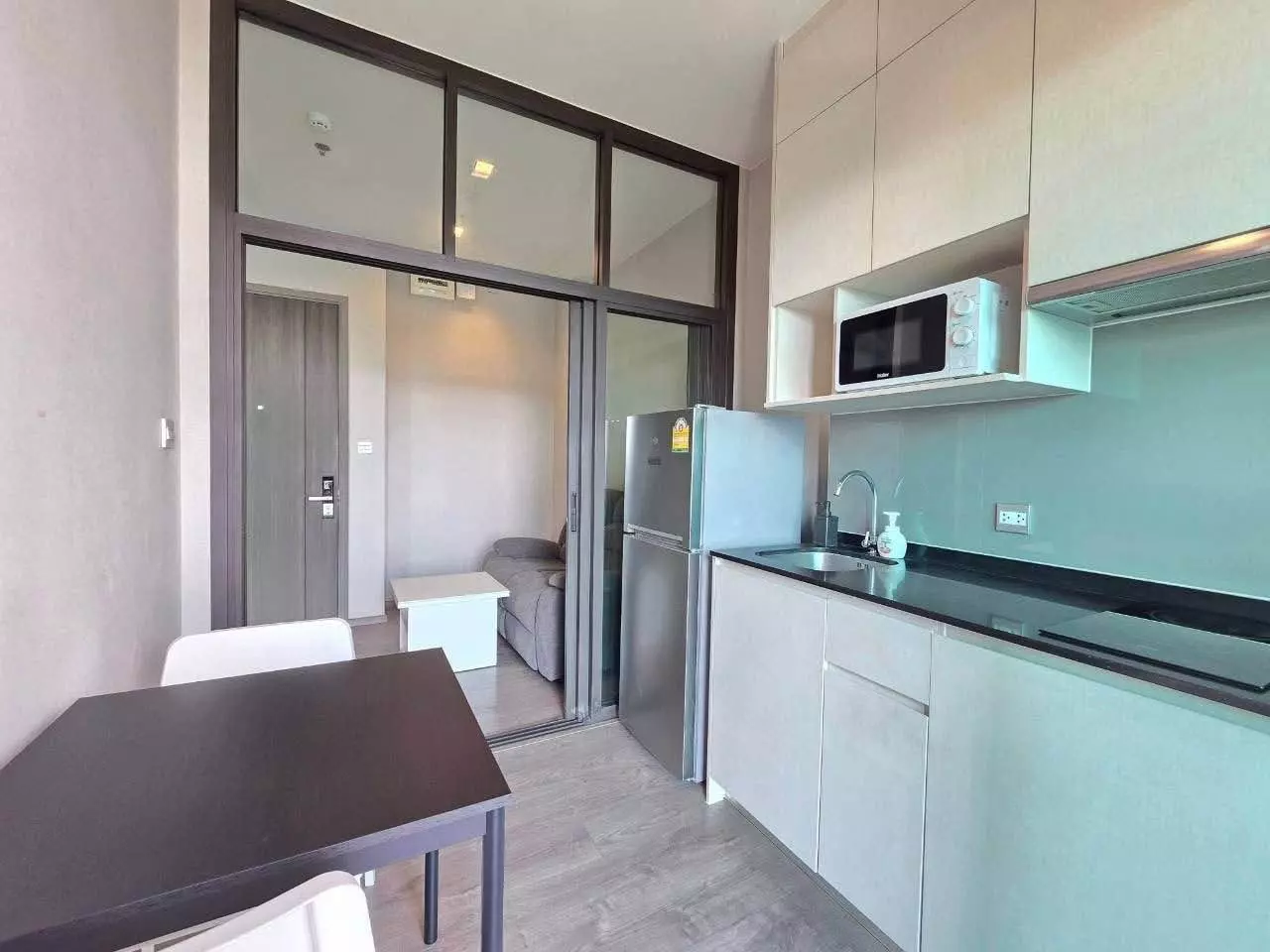 Open-plan kitchen and dining area in Whizdom Avenue Ratchada-Ladprao with dark wood table and granite countertops