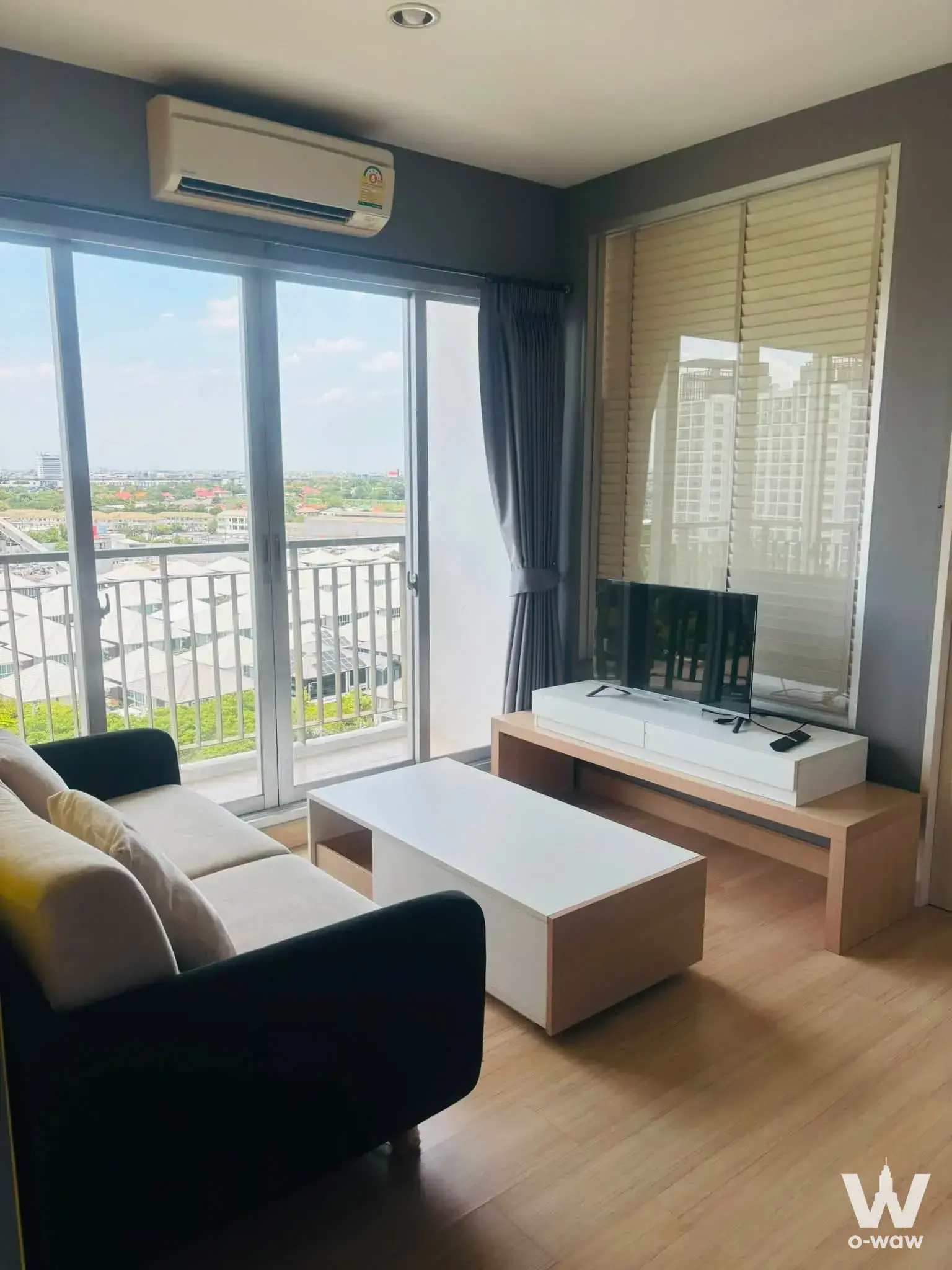 Charcoal-walled living room with city view balcony in The Parkland Srinakarin Lakeside condo