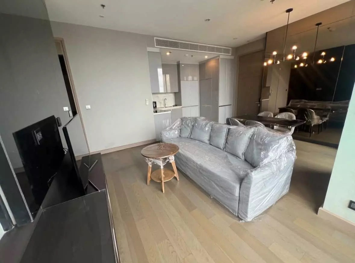 Spacious living room in a THE ESSE at SINGHA COMPLEX condo with grey sofa and open-plan dining area