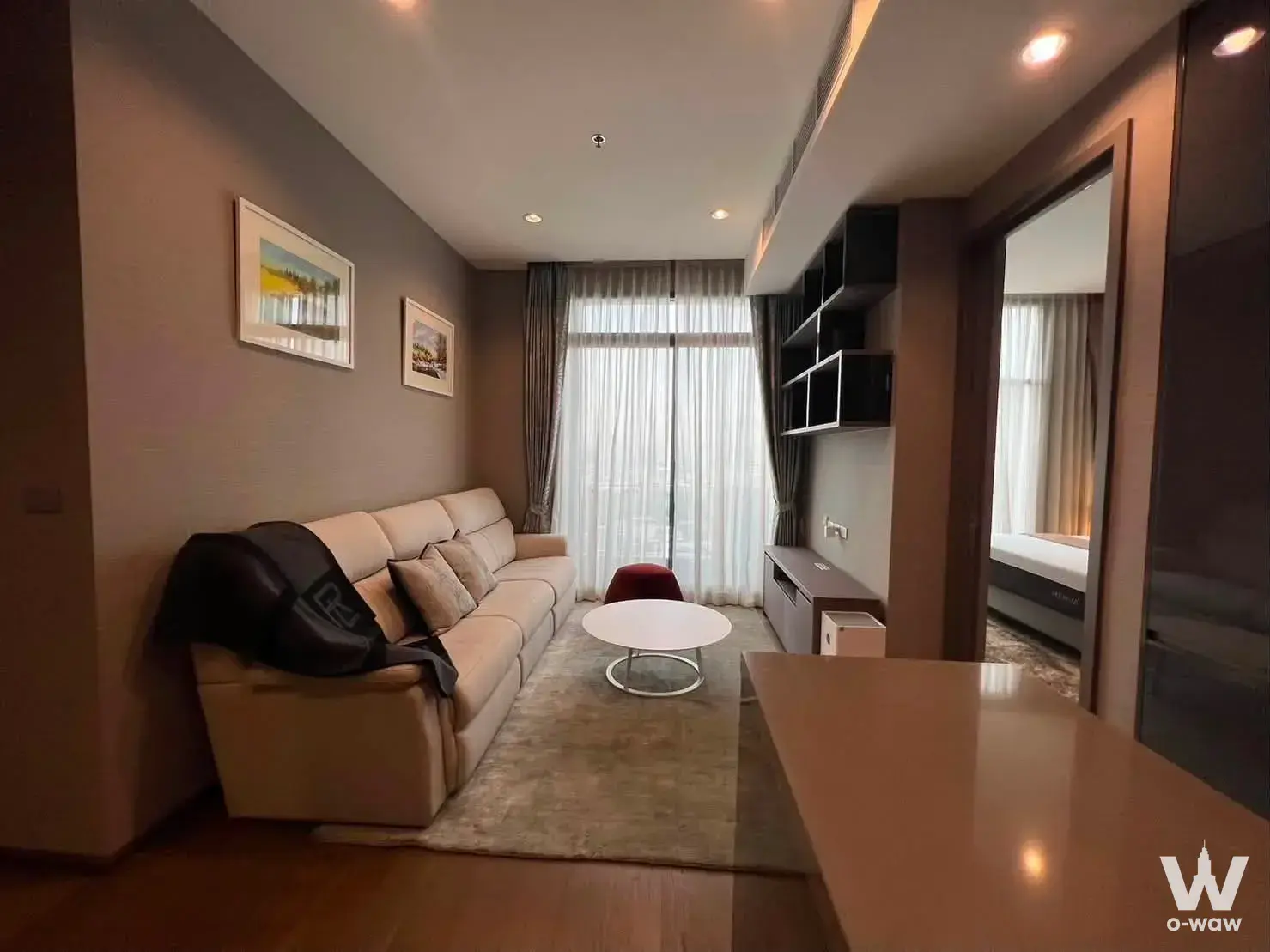 Furnished living room with beige sofa and floor-to-ceiling glass doors in a 2-bed unit at The Diplomat Sathorn