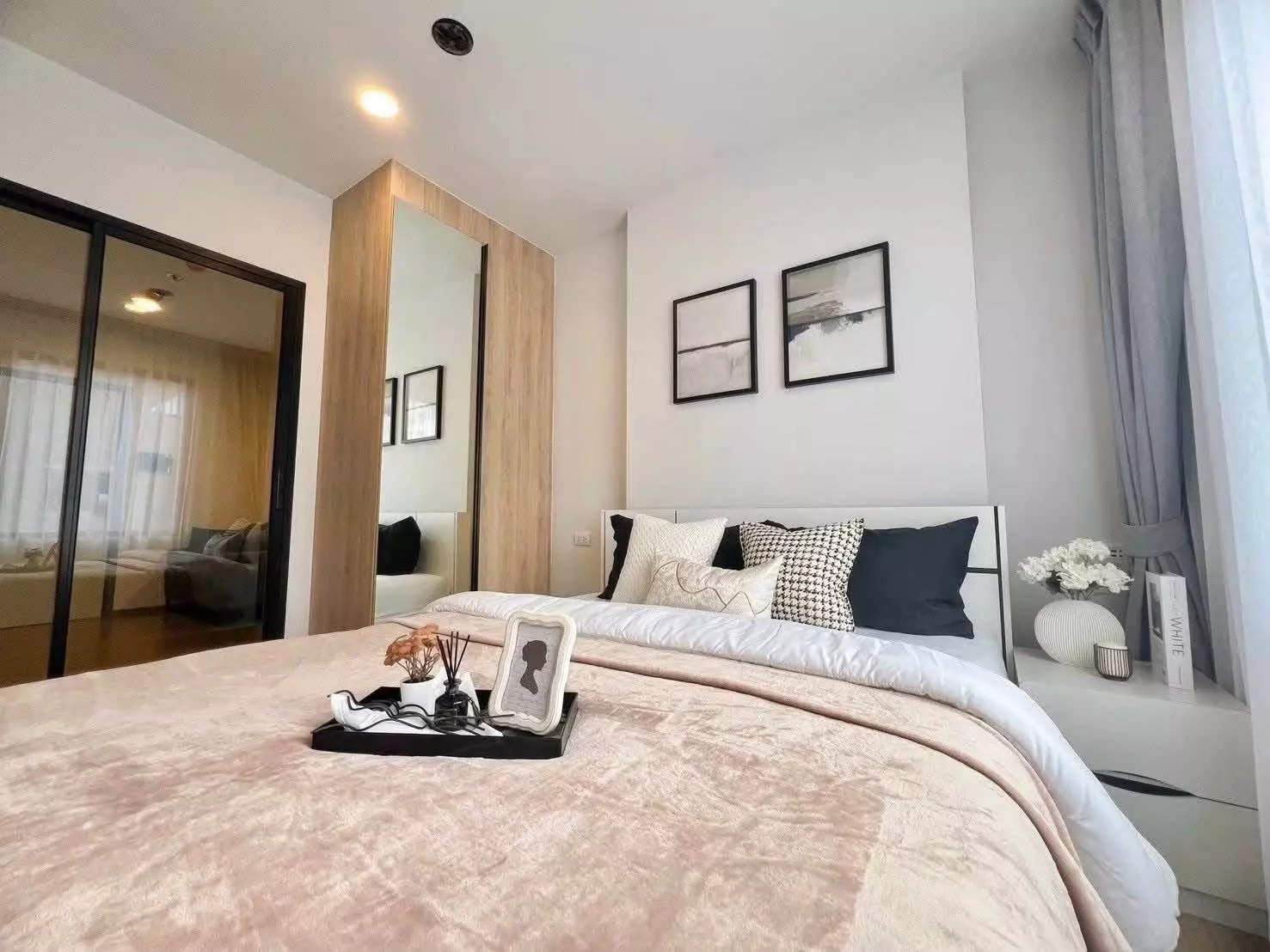 Bedroom in a Chewathai Pinklao condo with a queen bed, light wood wardrobe, and grey curtains